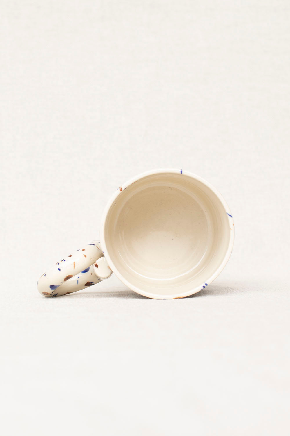 White ceramic mug with blue speckles on a white background