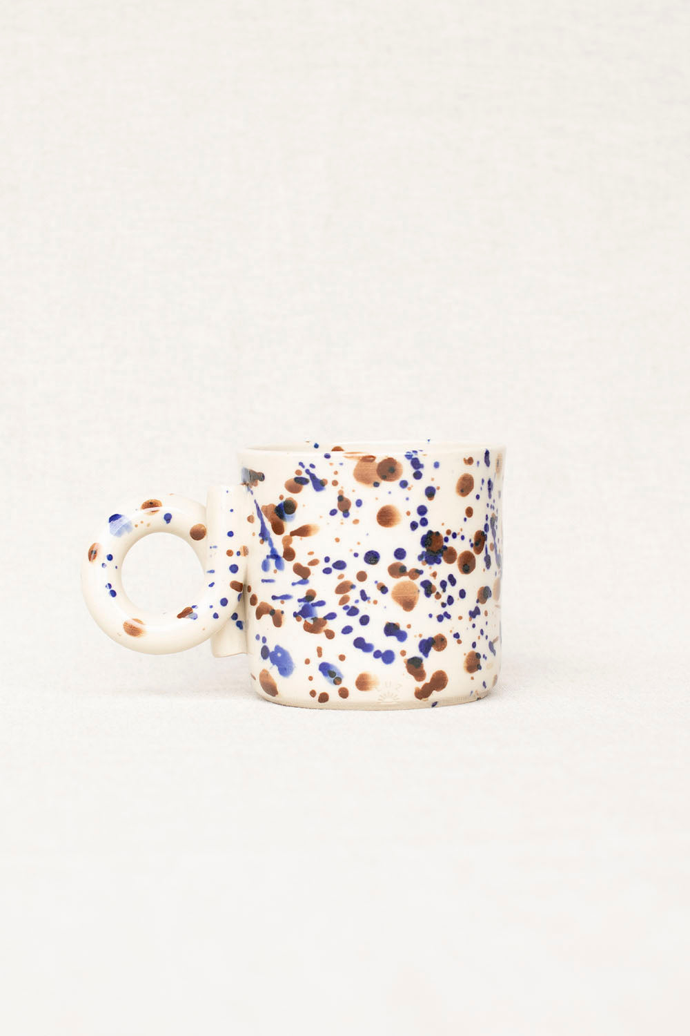 White mug with multicolored speckled pattern on a white background