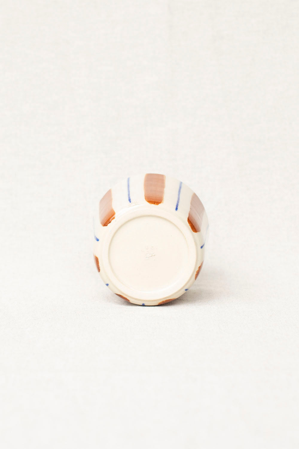 Small ceramic vase with striped design on a white background