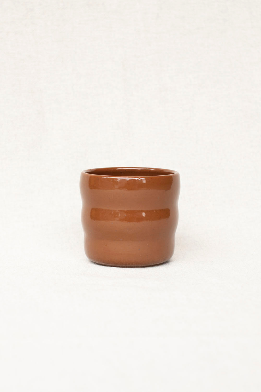 Brown ceramic cup with a horizontal stripe on a white background