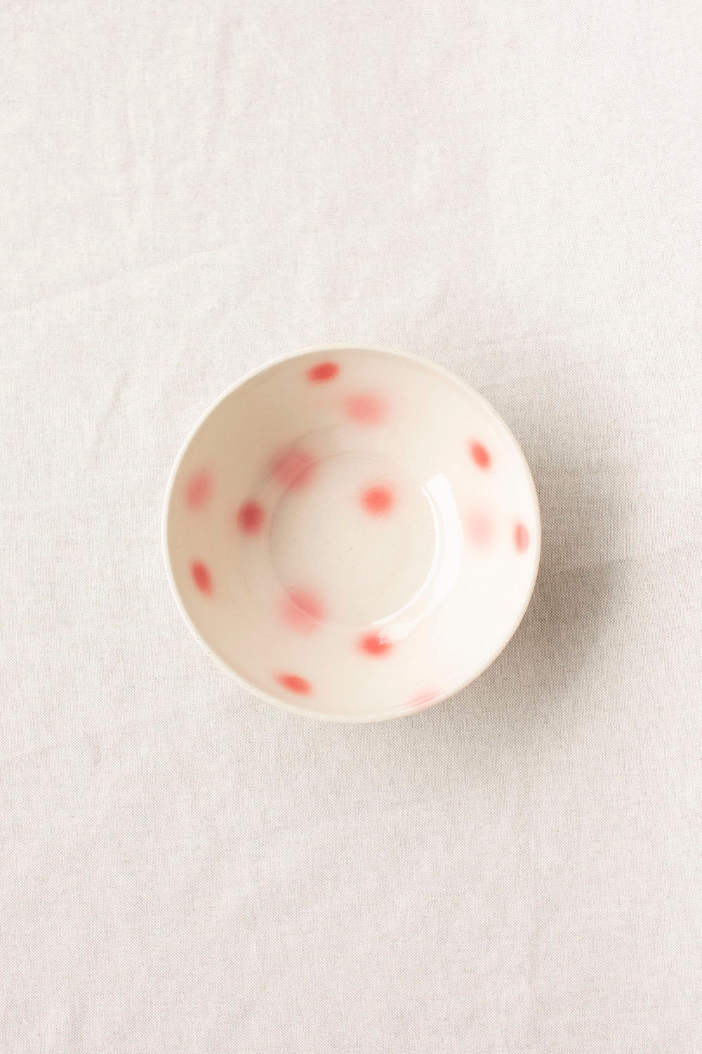 Round ceramic object with red speckles on a light gray background