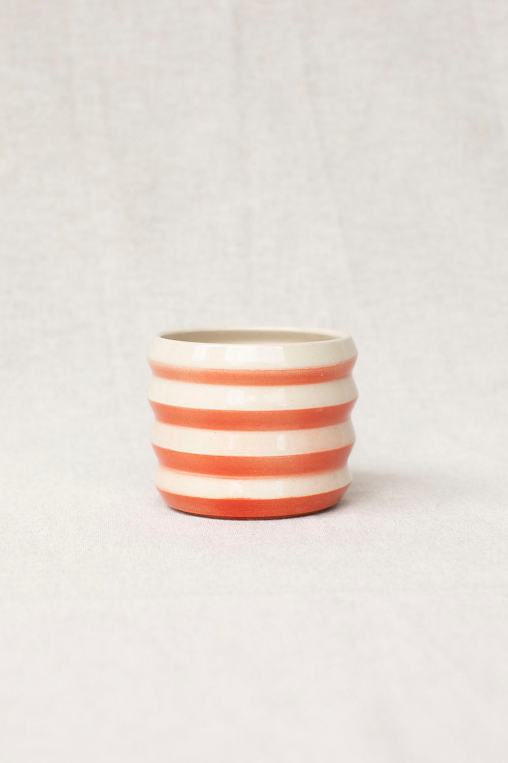 Ceramic pot with red and white stripes on a light gray background