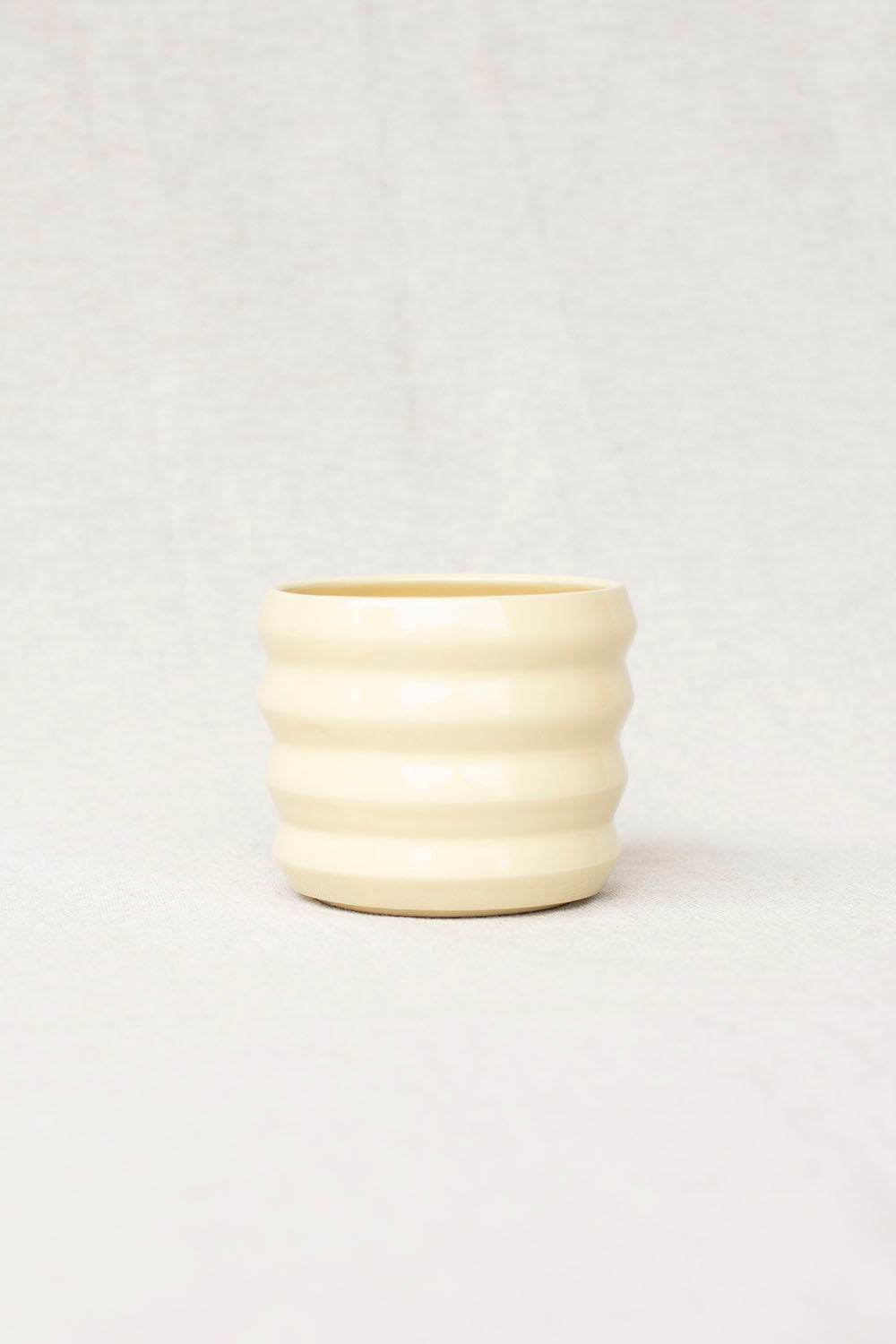 White ribbed ceramic pot on a light gray background