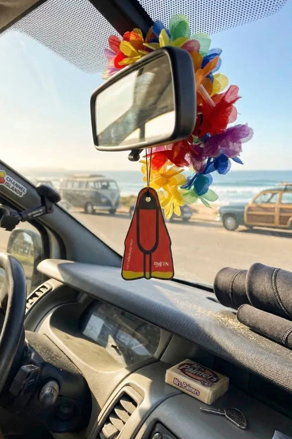 Car interior with a colorful fin-shaped car air freshener hanging from the rearview mirror.