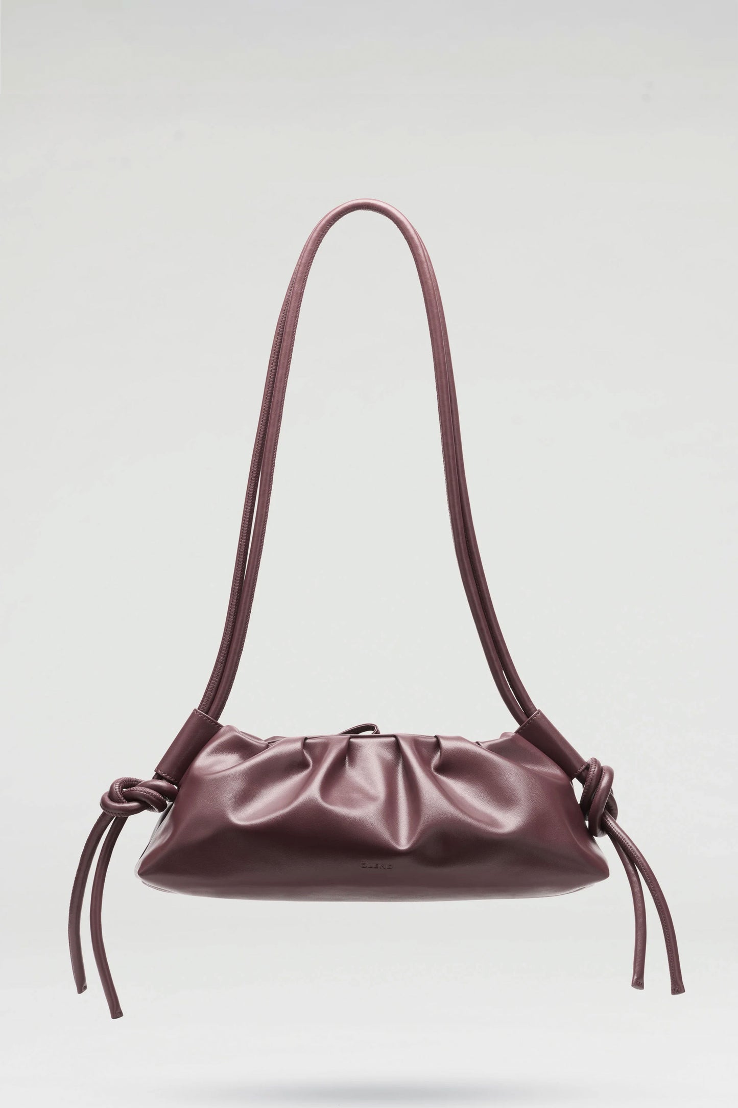 Chocolate ÖLEND dumpling handbag with a strap on a light gray background