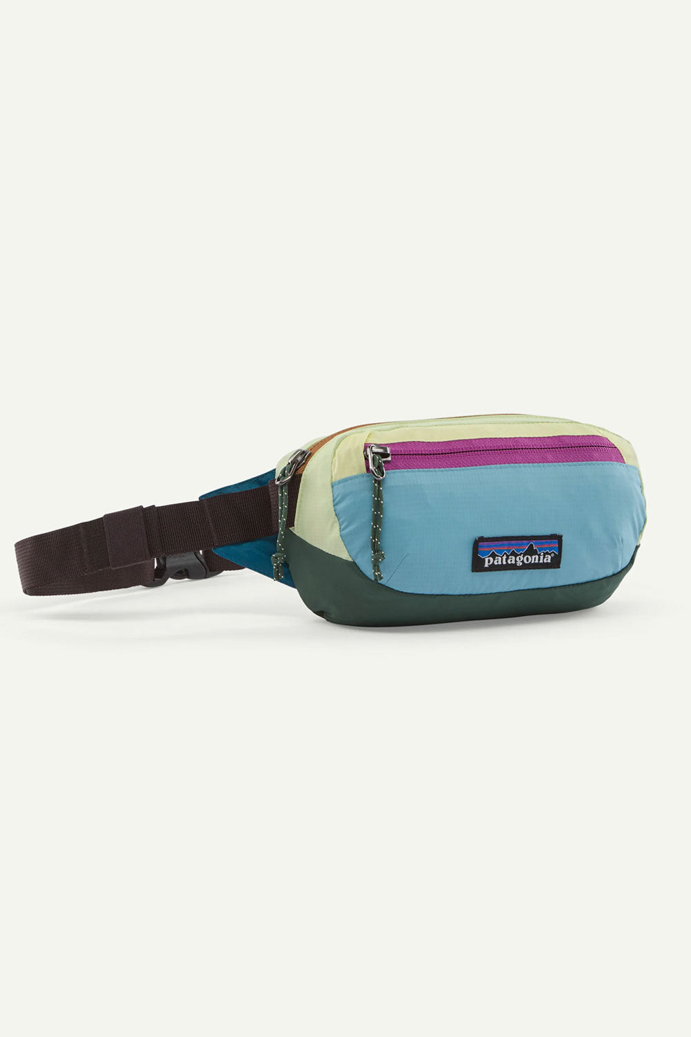 A Patagonia colorblock fanny pack with a light blue, cream, dark green, and purple color-blocked design, featuring a dark brown adjustable strap and a Patagonia logo patch on the front.