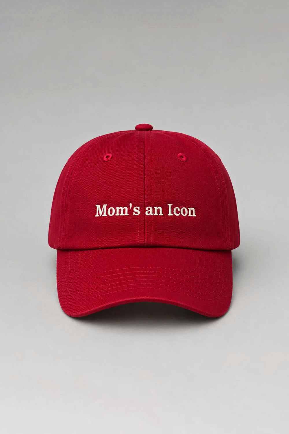 A red baseball cap with 'Mom's an Icon' embroidered in white on the front, set against a neutral gray background.