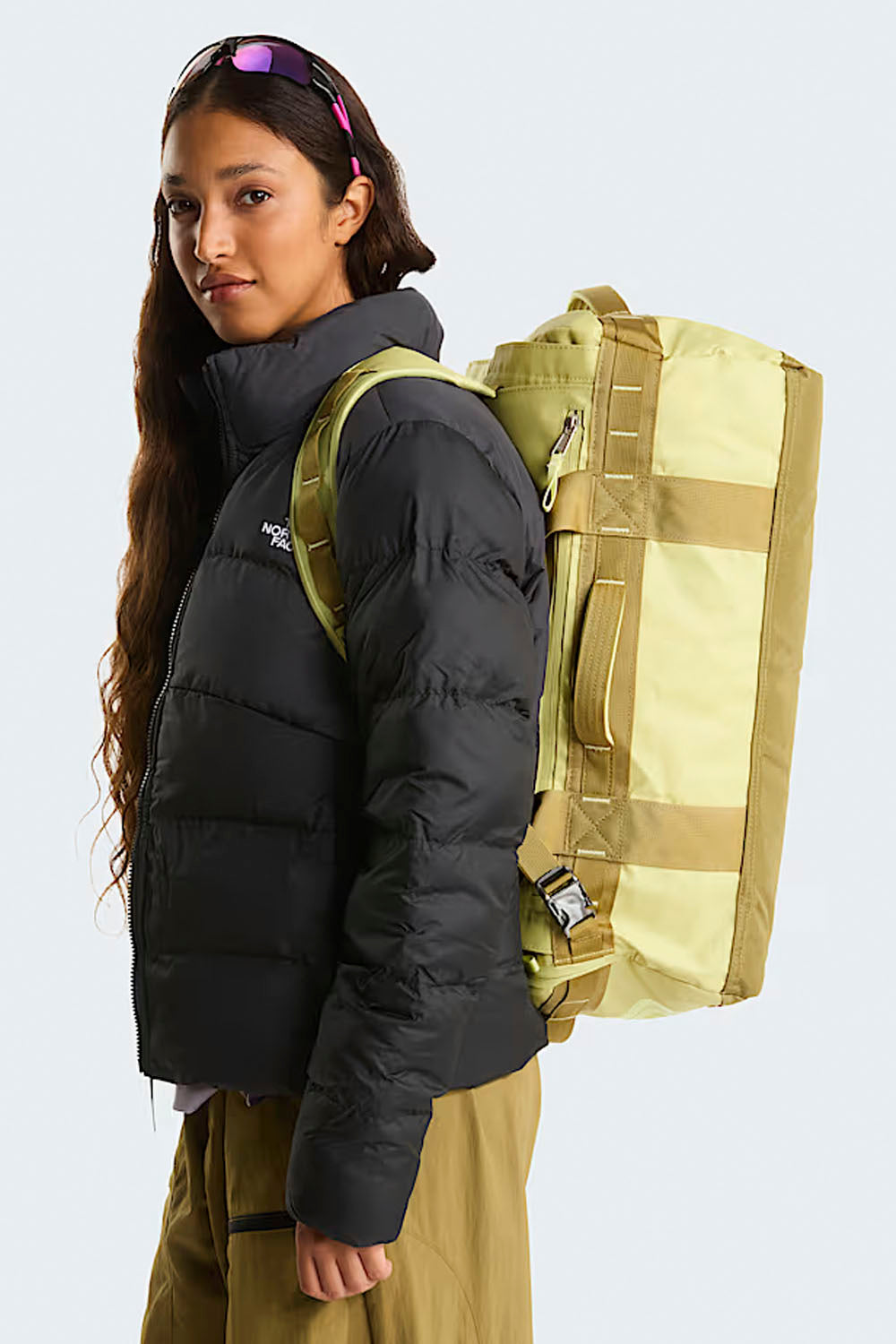 Person wearing a black puffer jacket and yellow backpack on a white background