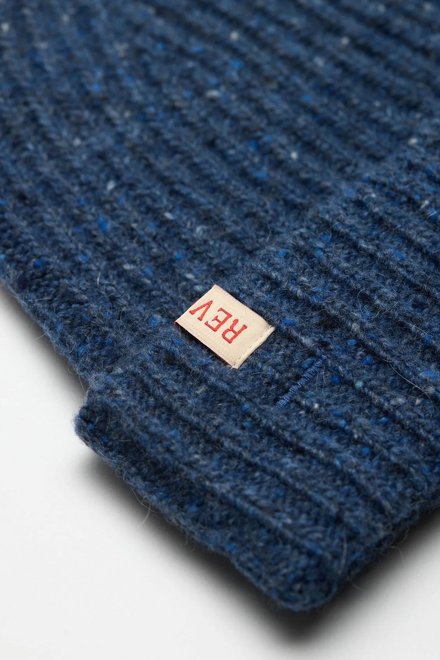Close-up of Revolution blue textured beanie with a red 'REV' label Pukas Surf Shop