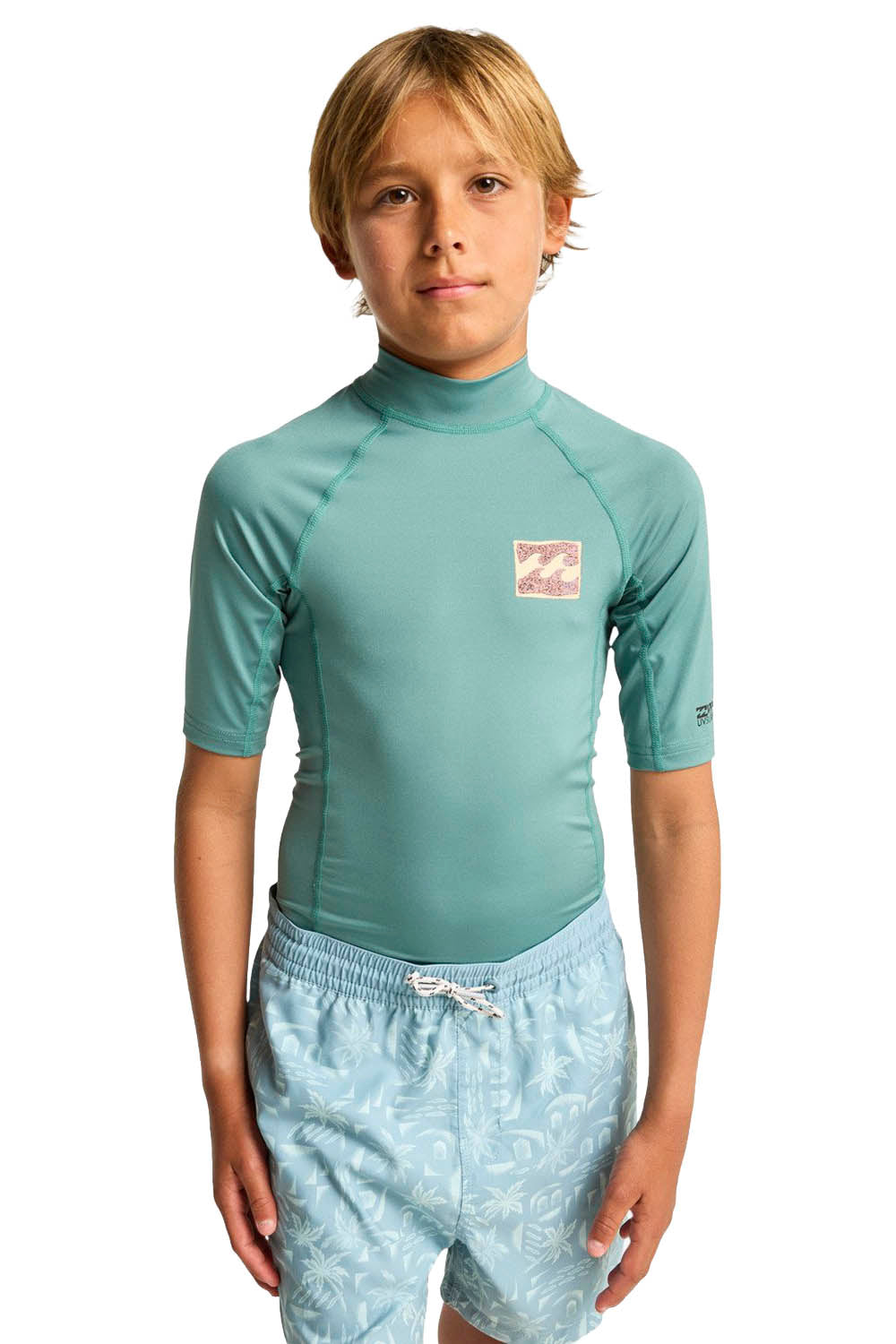 Child wearing a teal rash guard and light blue patterned shorts on a white background