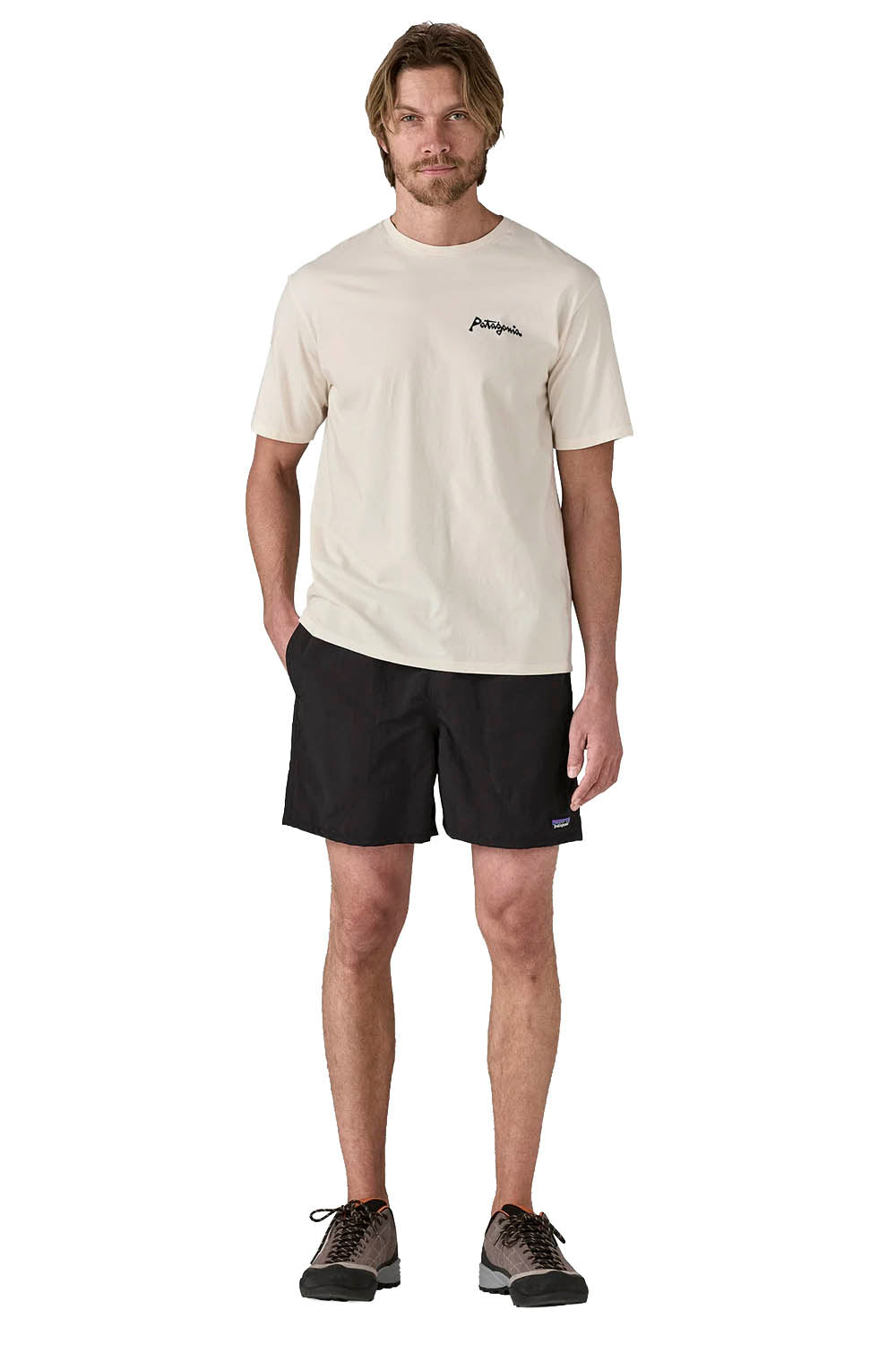 A man modeling a Patagonia short-sleeve t-shirt in off-white and black shorts, standing against a solid white background.