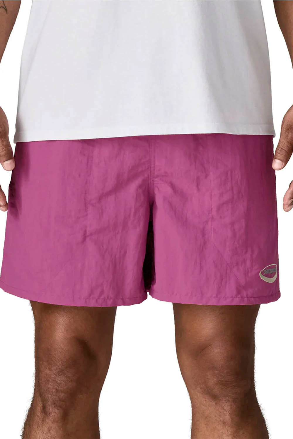 A close-up of a person wearing mauve-purple athletic shorts and a white t-shirt, cropped from the chest down against a plain white background.