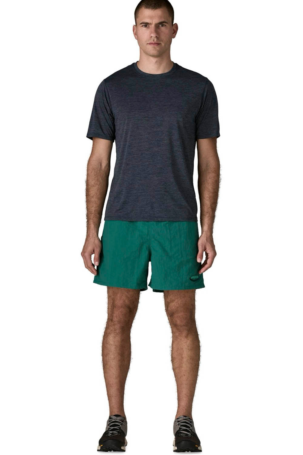 A man modeling a dark heather gray short-sleeve athletic t-shirt and green running shorts against a plain white background.