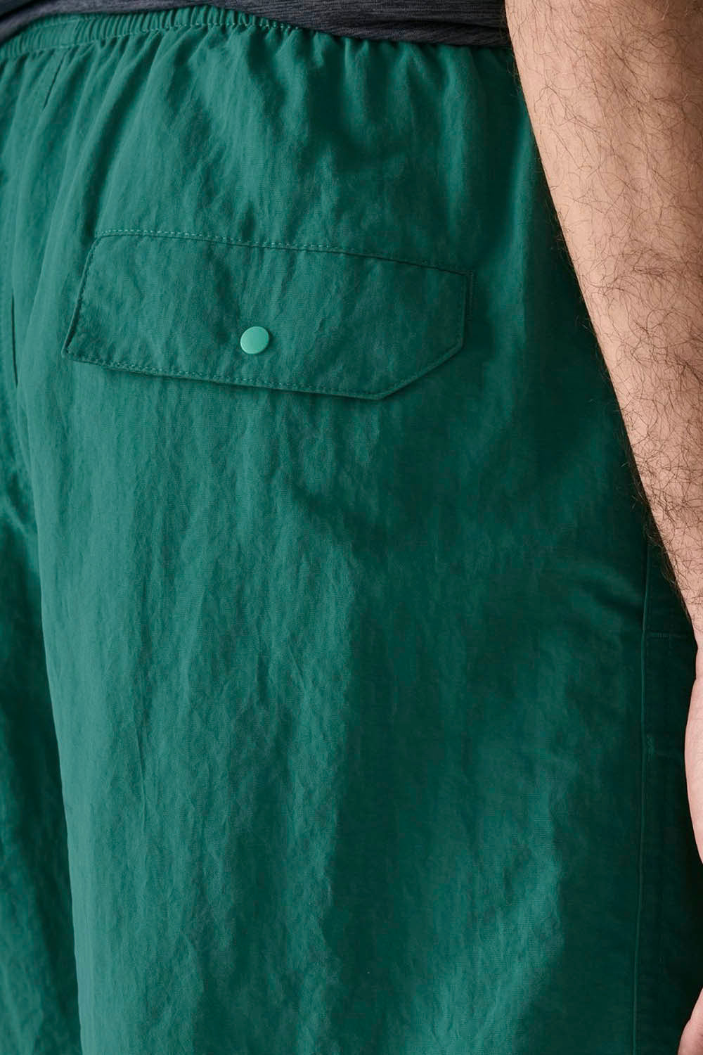 A man modeling a dark heather gray short-sleeve athletic t-shirt and green running shorts against a plain white background.