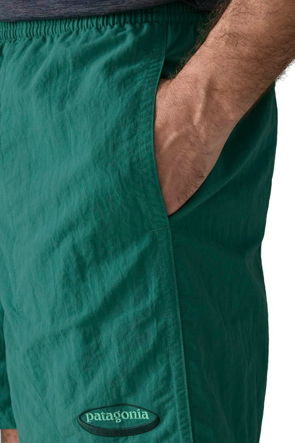 A man modeling a dark heather gray short-sleeve athletic t-shirt and green running shorts against a plain white background.
