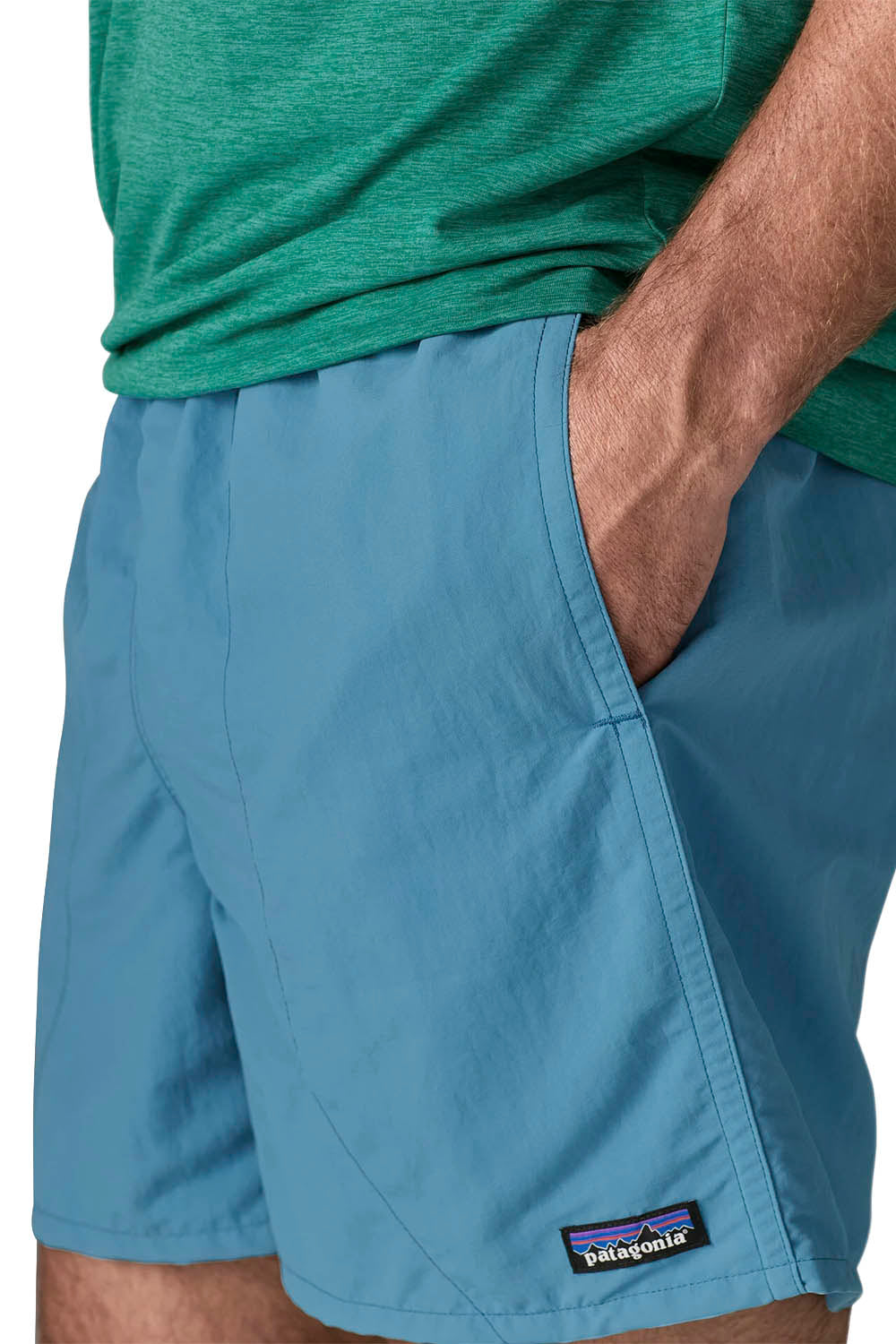 A man modeling a green short-sleeve athletic t-shirt and light blue shorts against a plain white background.