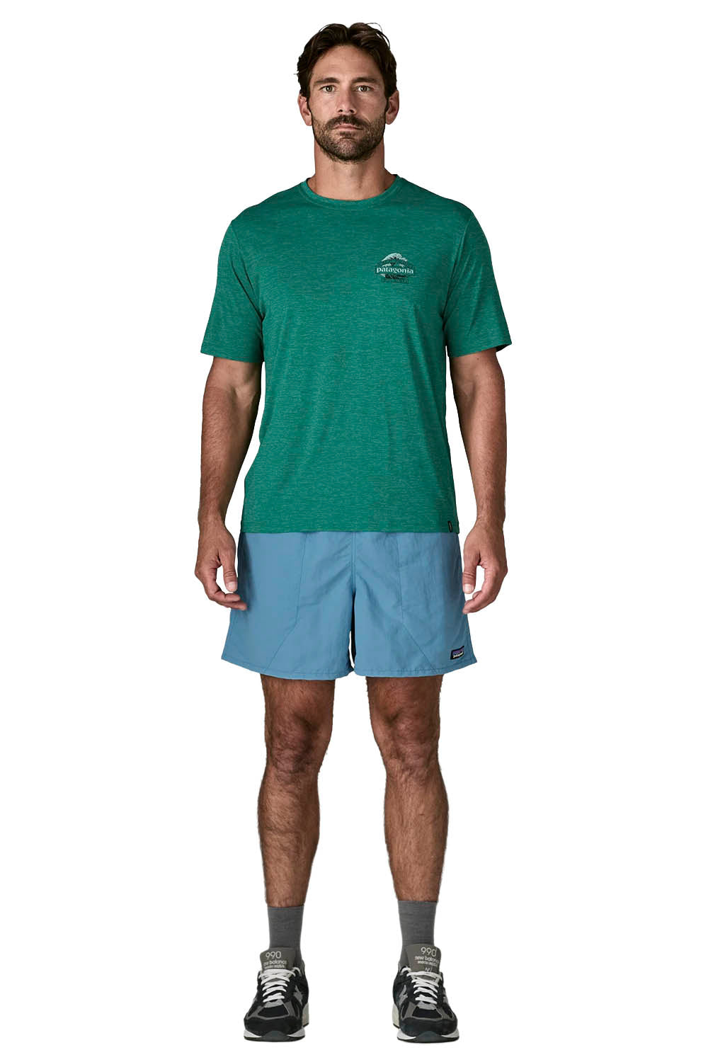 A man modeling a green short-sleeve athletic t-shirt and light blue shorts against a plain white background.