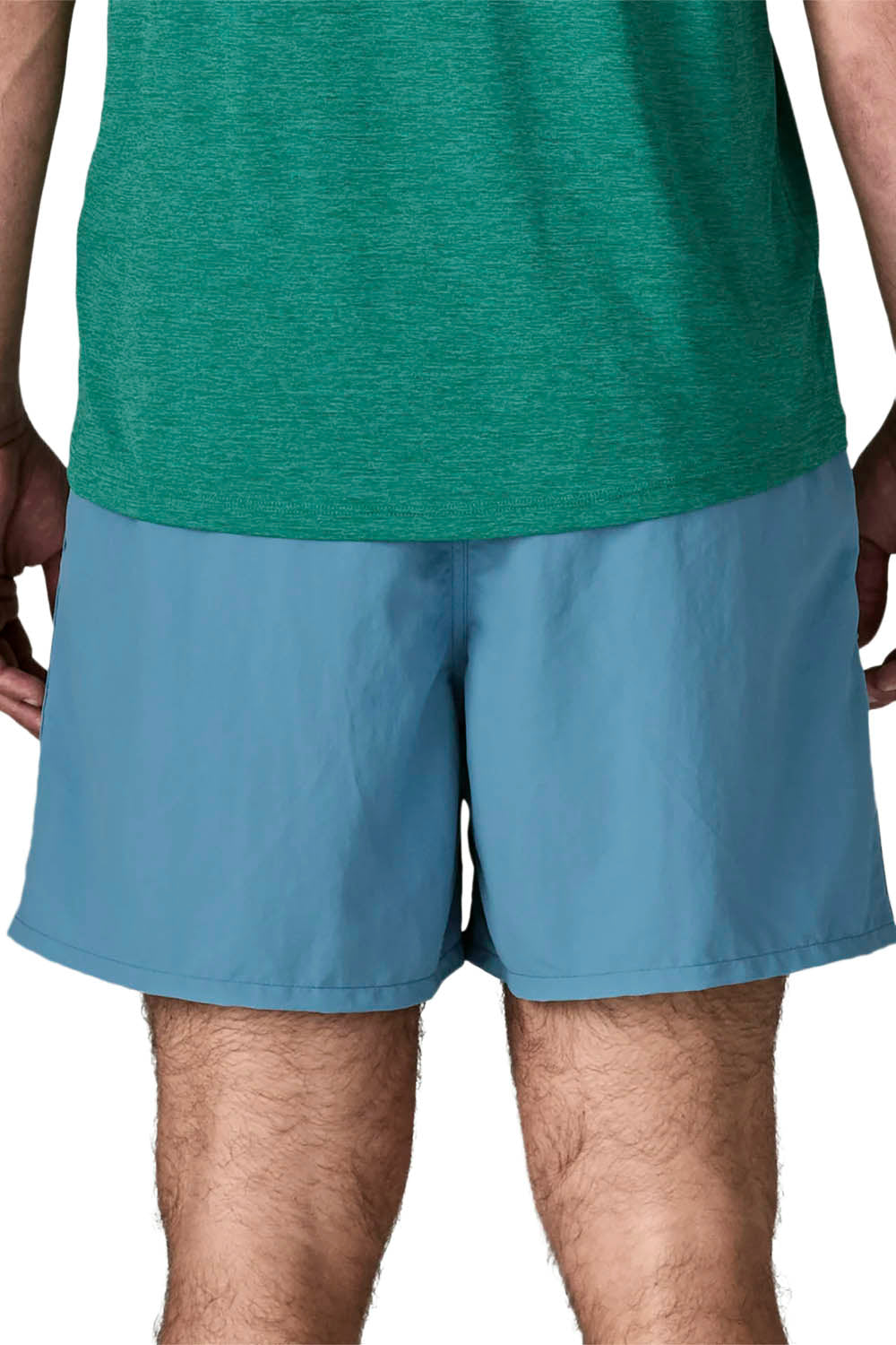 A man modeling a green short-sleeve athletic t-shirt and light blue shorts against a plain white background.