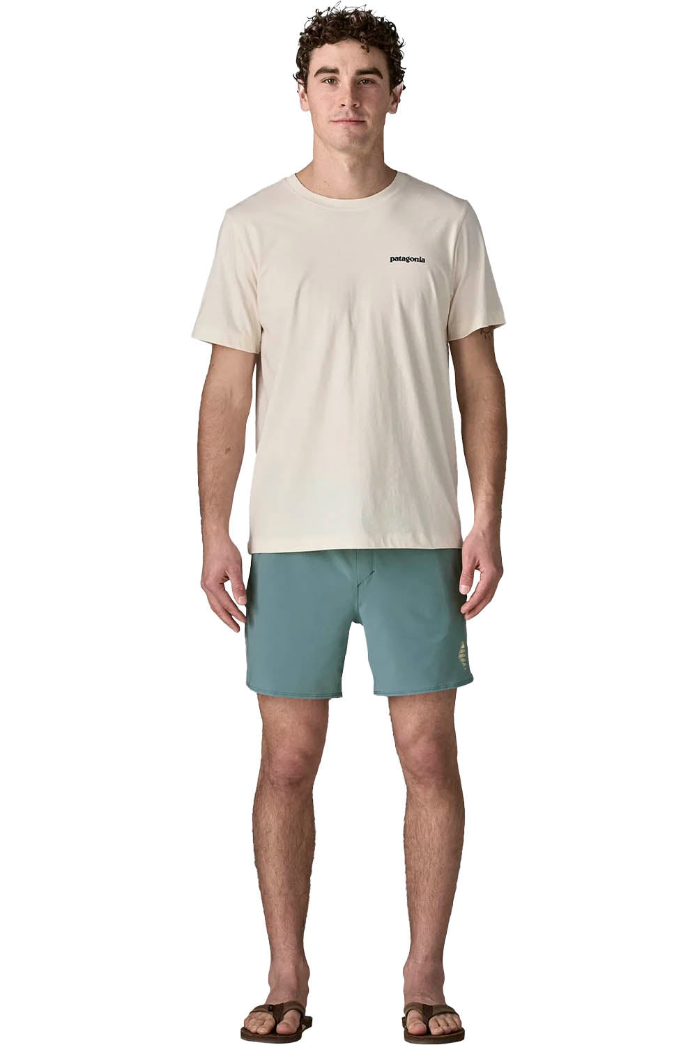 A man modeling a Patagonia short-sleeve t-shirt in cream and matching sage green shorts, standing against a plain white background.