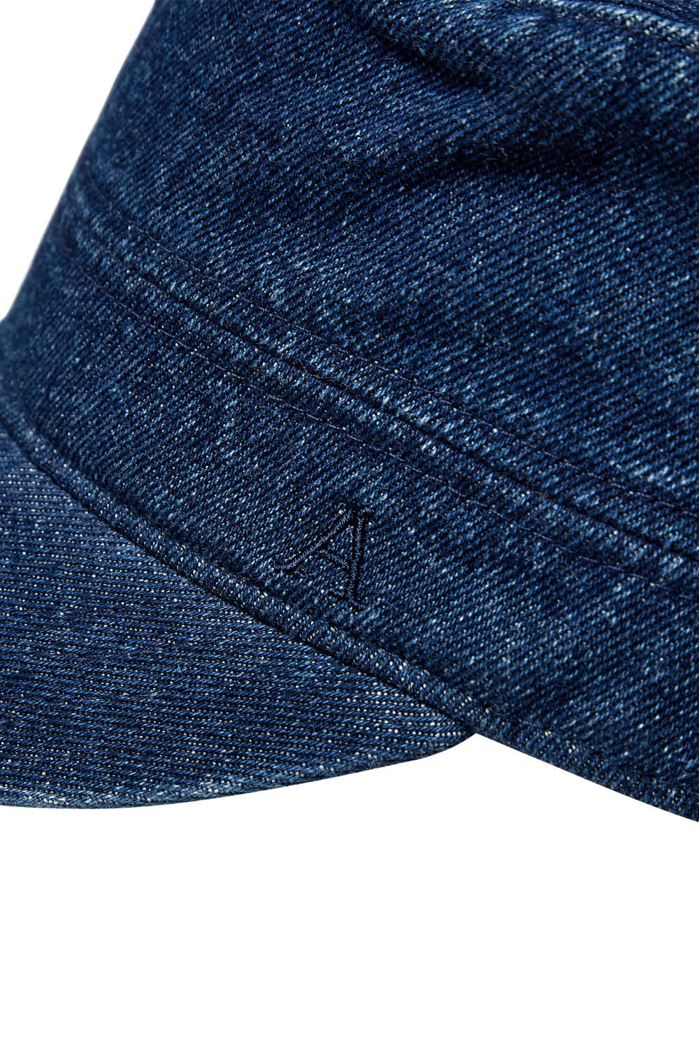 Close-up of a dark blue denim cap showing the fabric texture and a small embroidered logo on the side, set against a plain white background.