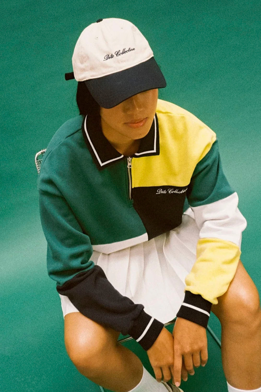 Person wearing a colorful tracksuit and cap on a green background
