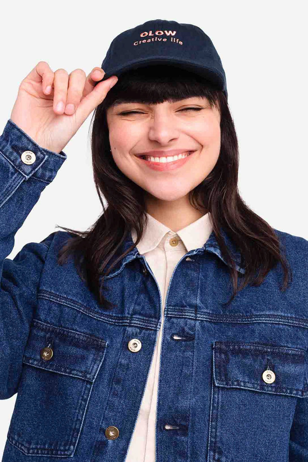 Person wearing a navy cap and denim jacket on a white background