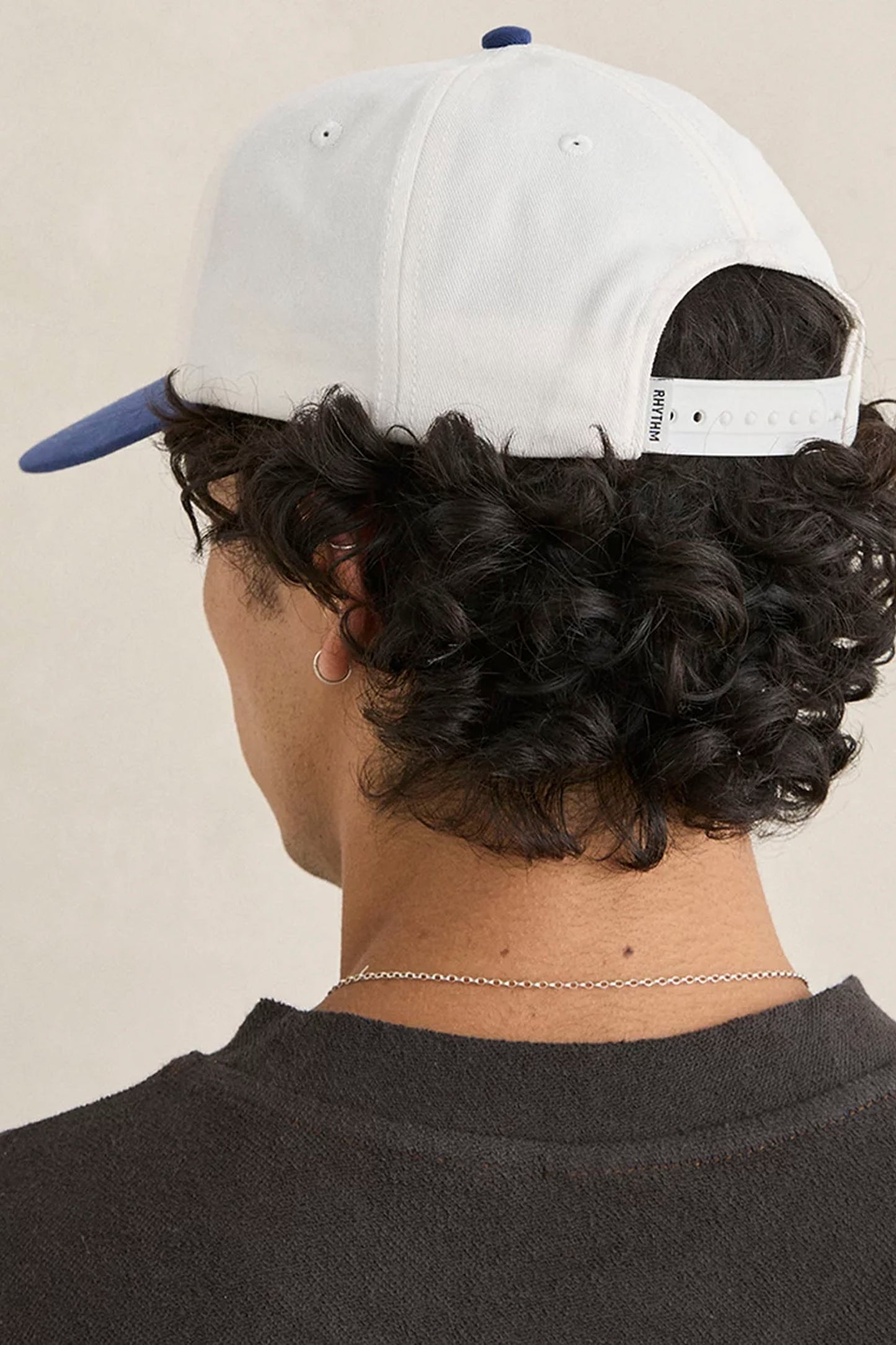 Person wearing Rhythm Slow Down cap with a logo and text on a neutral background