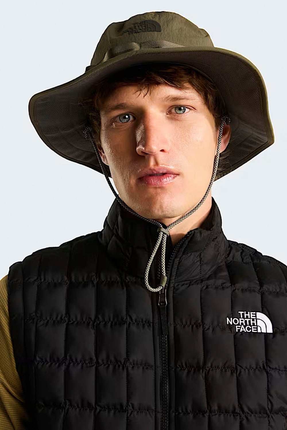 Person wearing a The North Face hat and black puffer vest on a white background