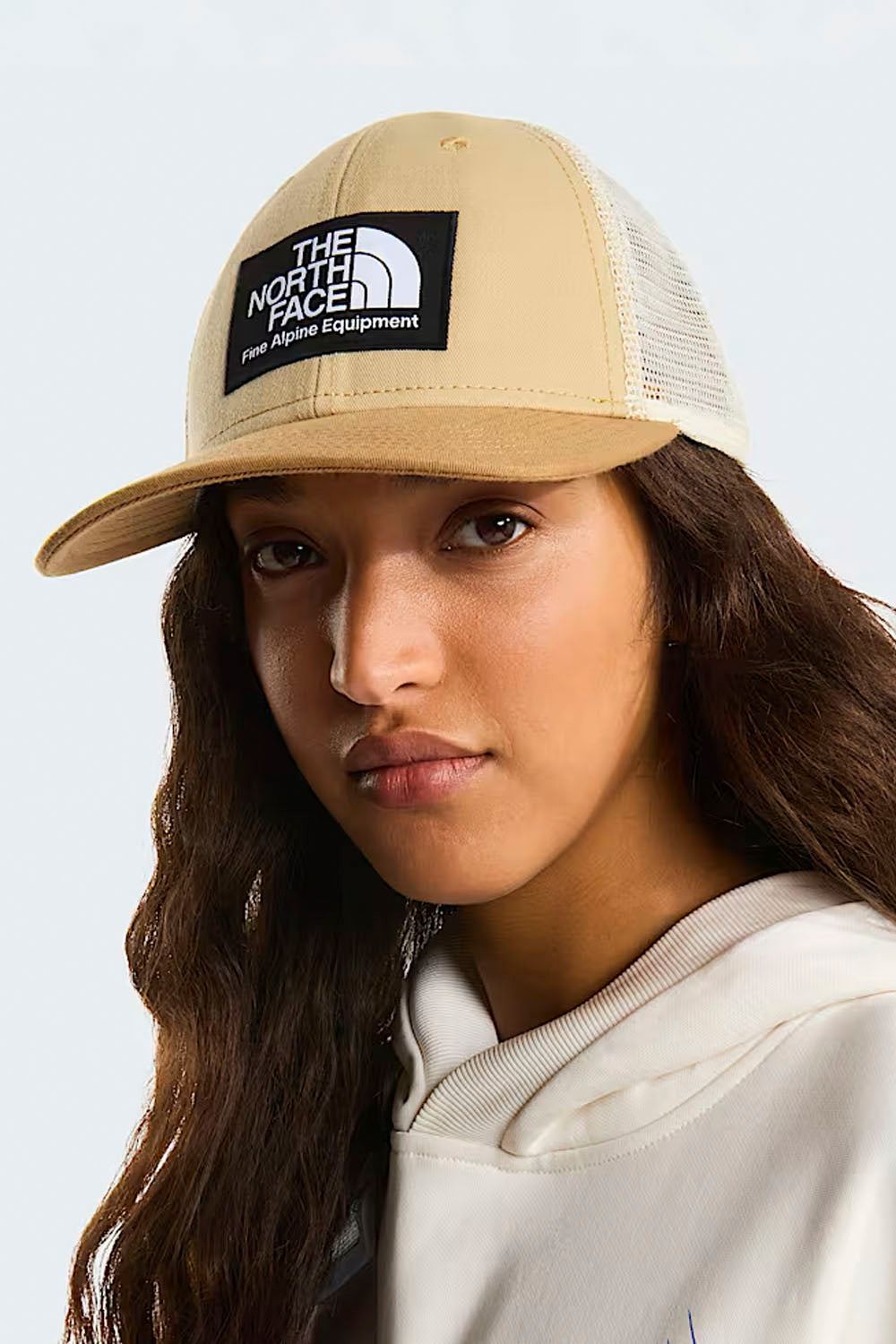 Person wearing a beige cap with 'The North Face' logo on a light gray background