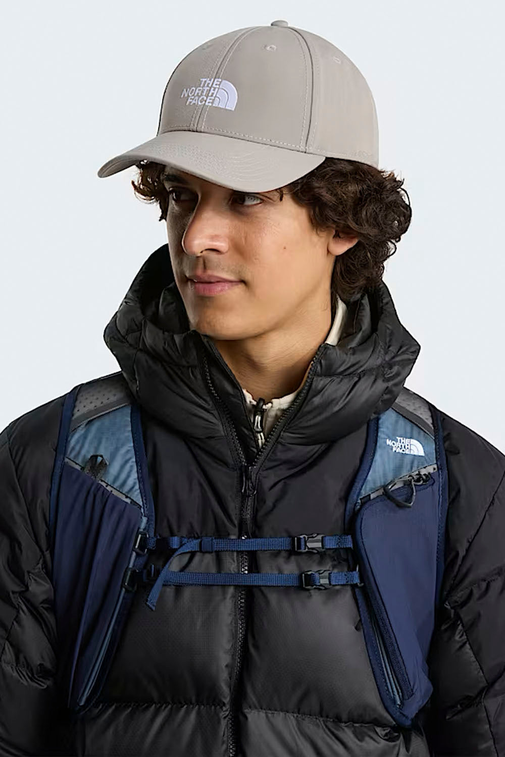 Person wearing a The North Face cap and jacket with a backpack on a white background