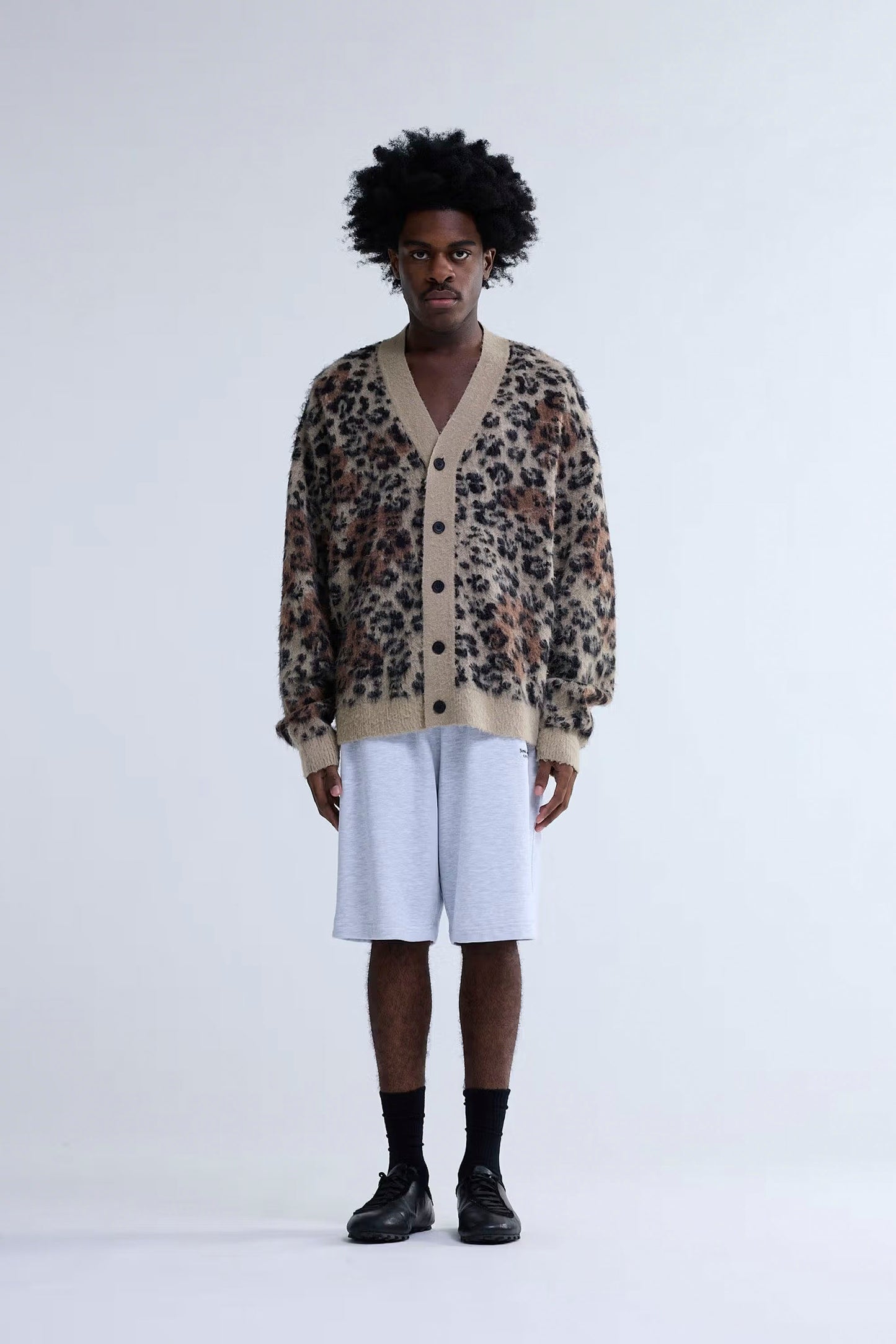 Person wearing New Amsterdam Surf Association Hibiscus Cardigan with white shorts on a plain background