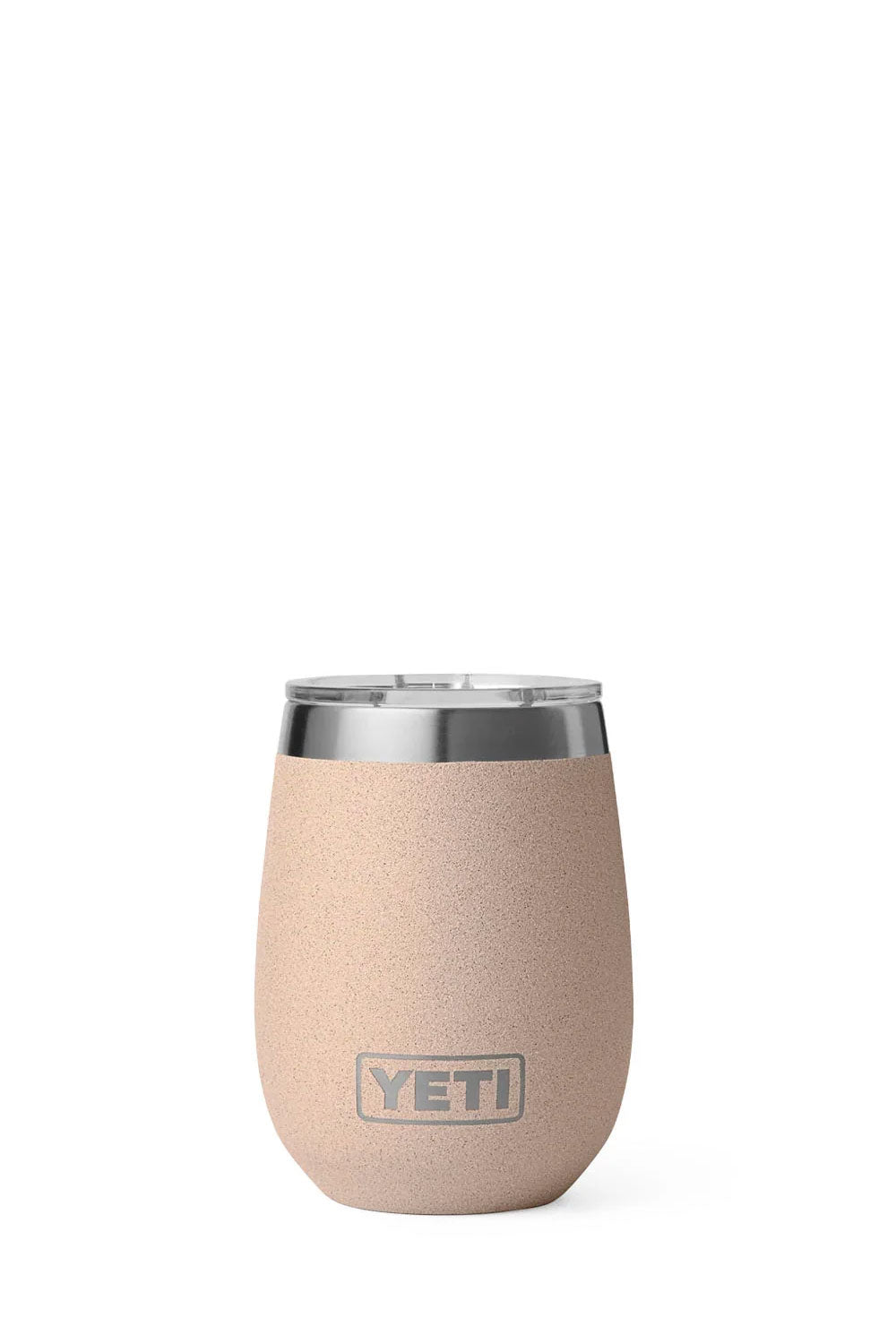A YETI stemless wine tumbler in a light peach-beige color with a brushed silver metal rim, shown next to its clear lid containing two ice cubes, on a white background.