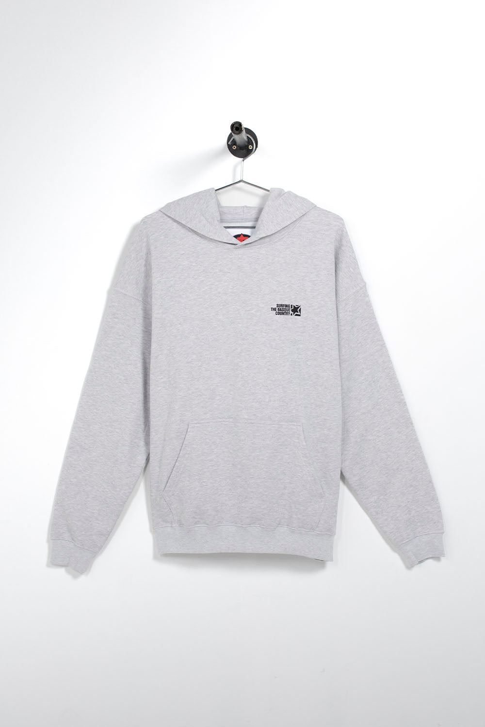 A light gray heather pullover hoodie with a small black graphic logo on the left chest, hanging on a white wall hook.