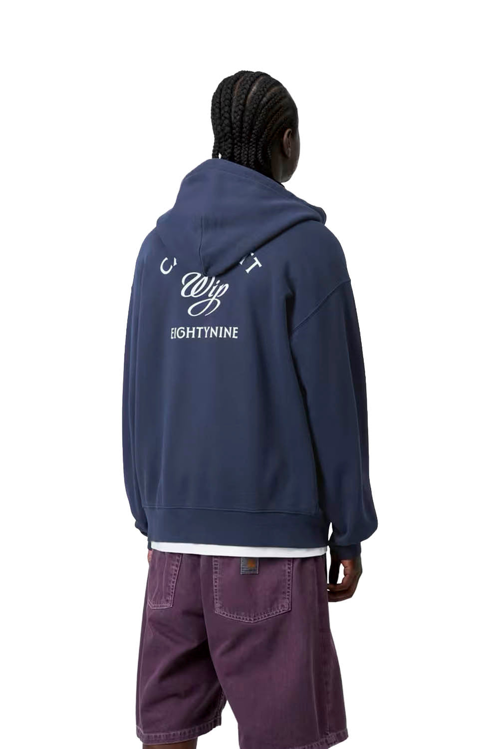 Person wearing a navy blue hoodie with white text on the back, standing against a white background.