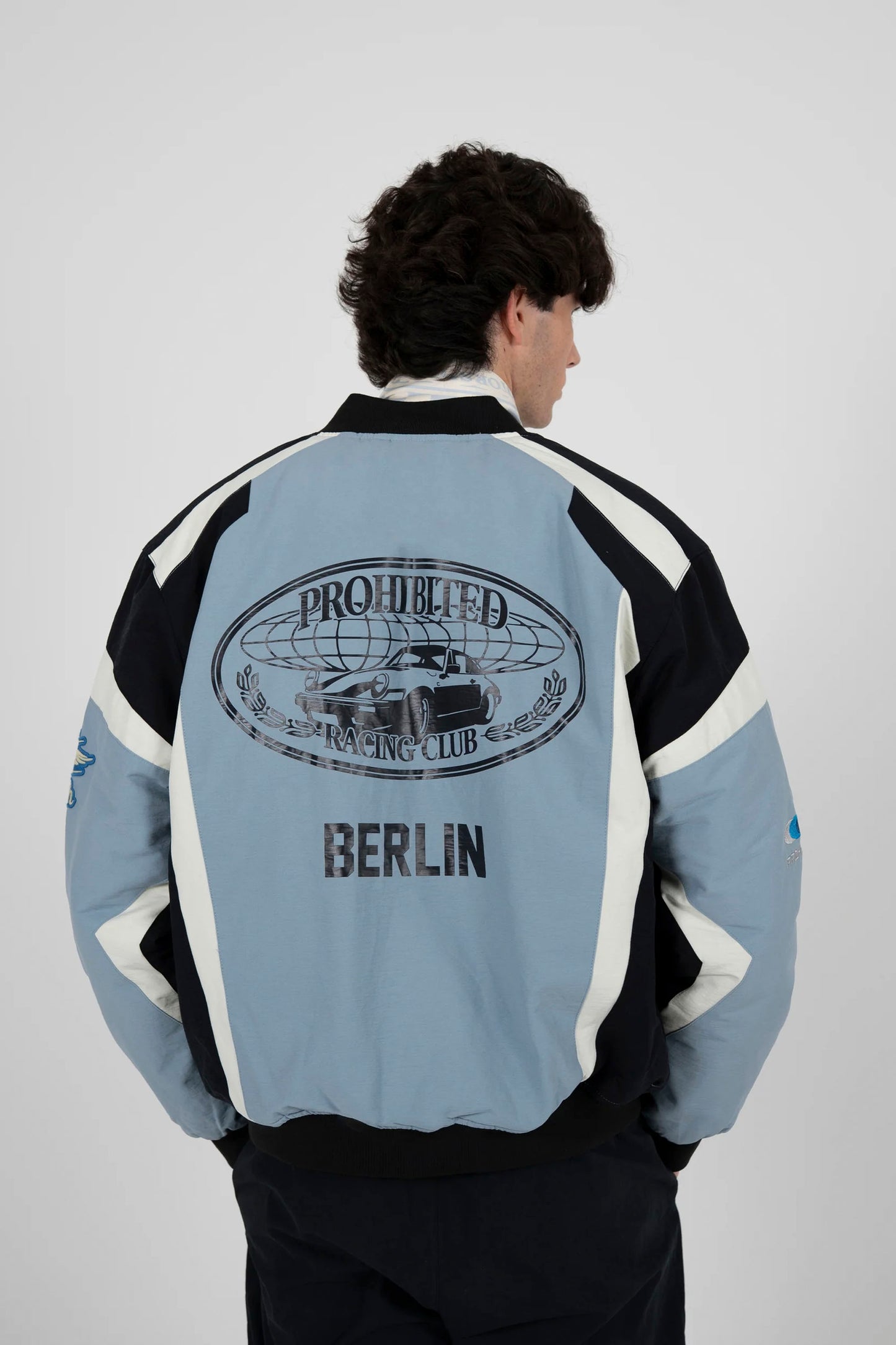 Man wearing blue PROHIBITED Hyperlane racing jacket