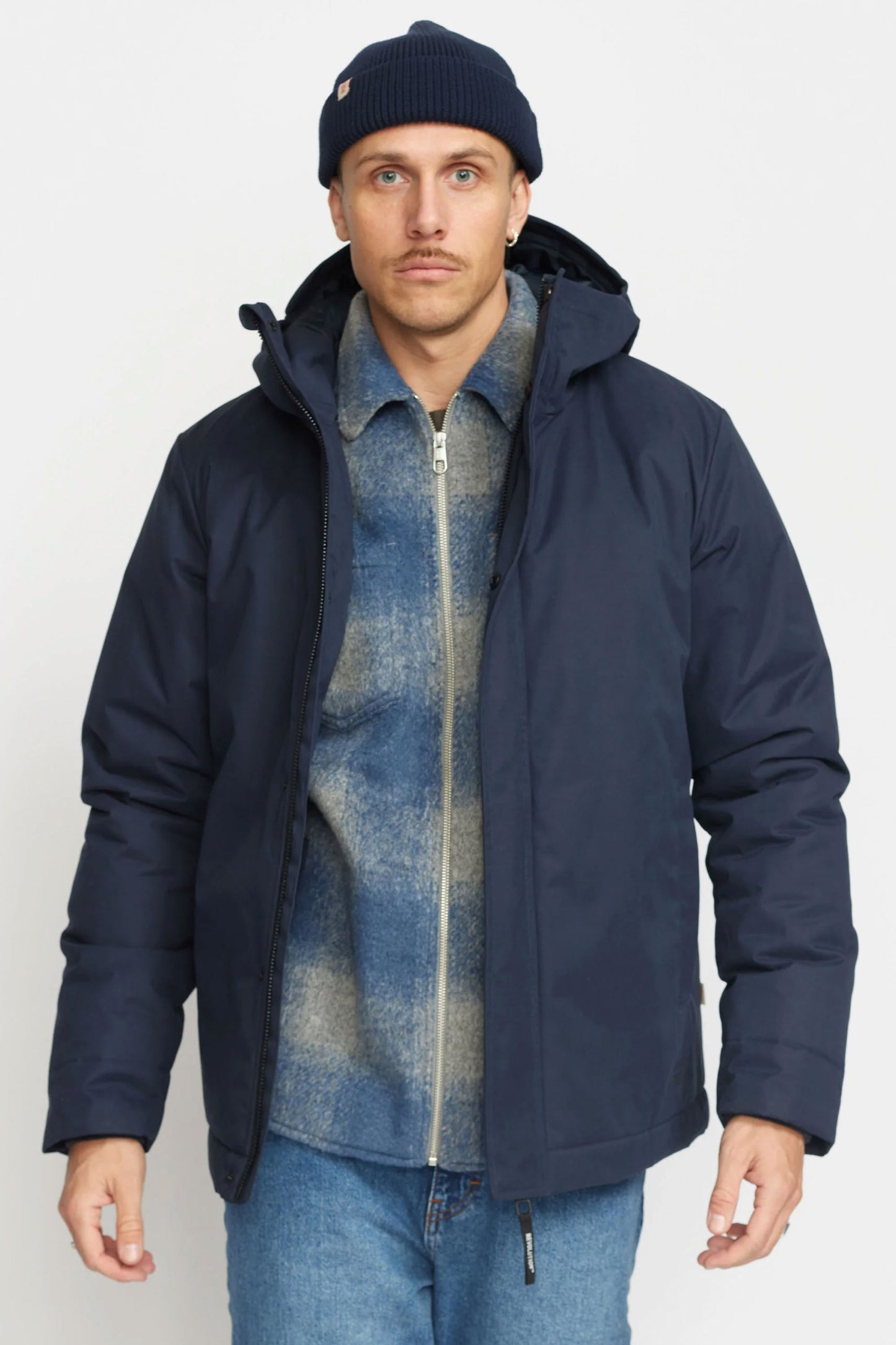 Man wearing a Revolution navy coat, denim shirt, and blue jeans Pukas Surf Shop