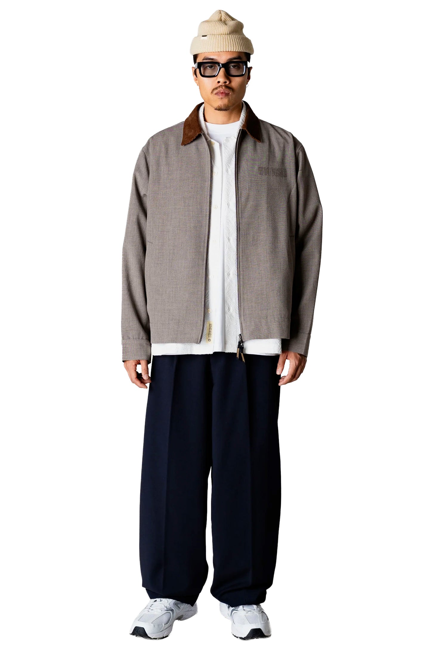 Man wearing a Woodbird Wbpon Guan Work jacket, white shirt, dark pants, and white sneakers on a white background