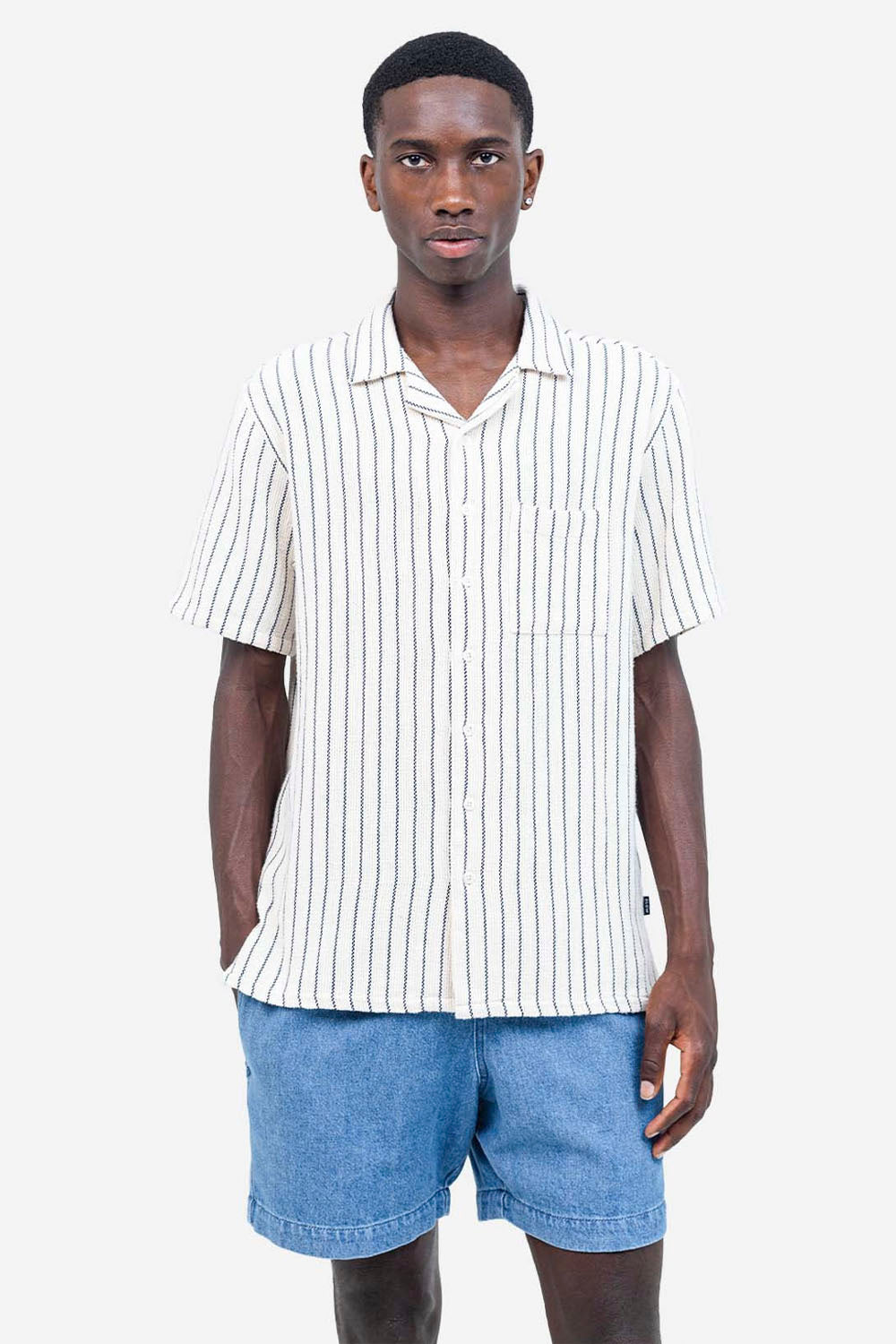 Man wearing a striped shirt and blue shorts on a white background