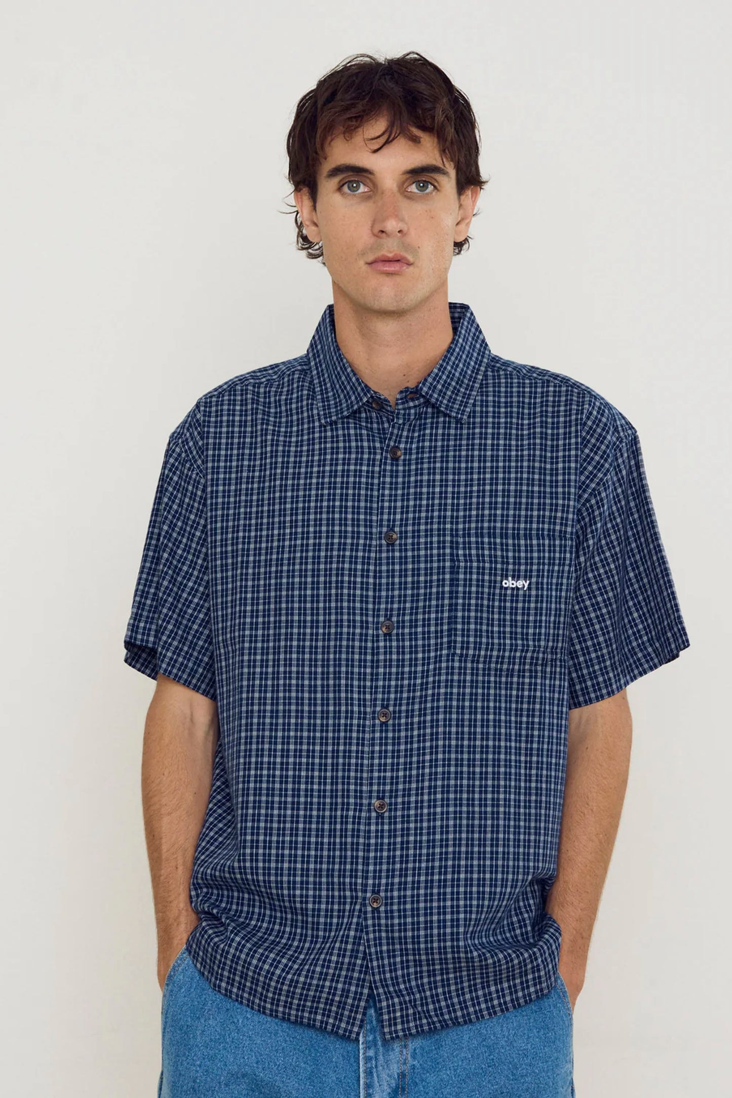 Man wearing a Navy OBEY Bigwig Ian short-sleeve shirt shirt with a small logo on a white background