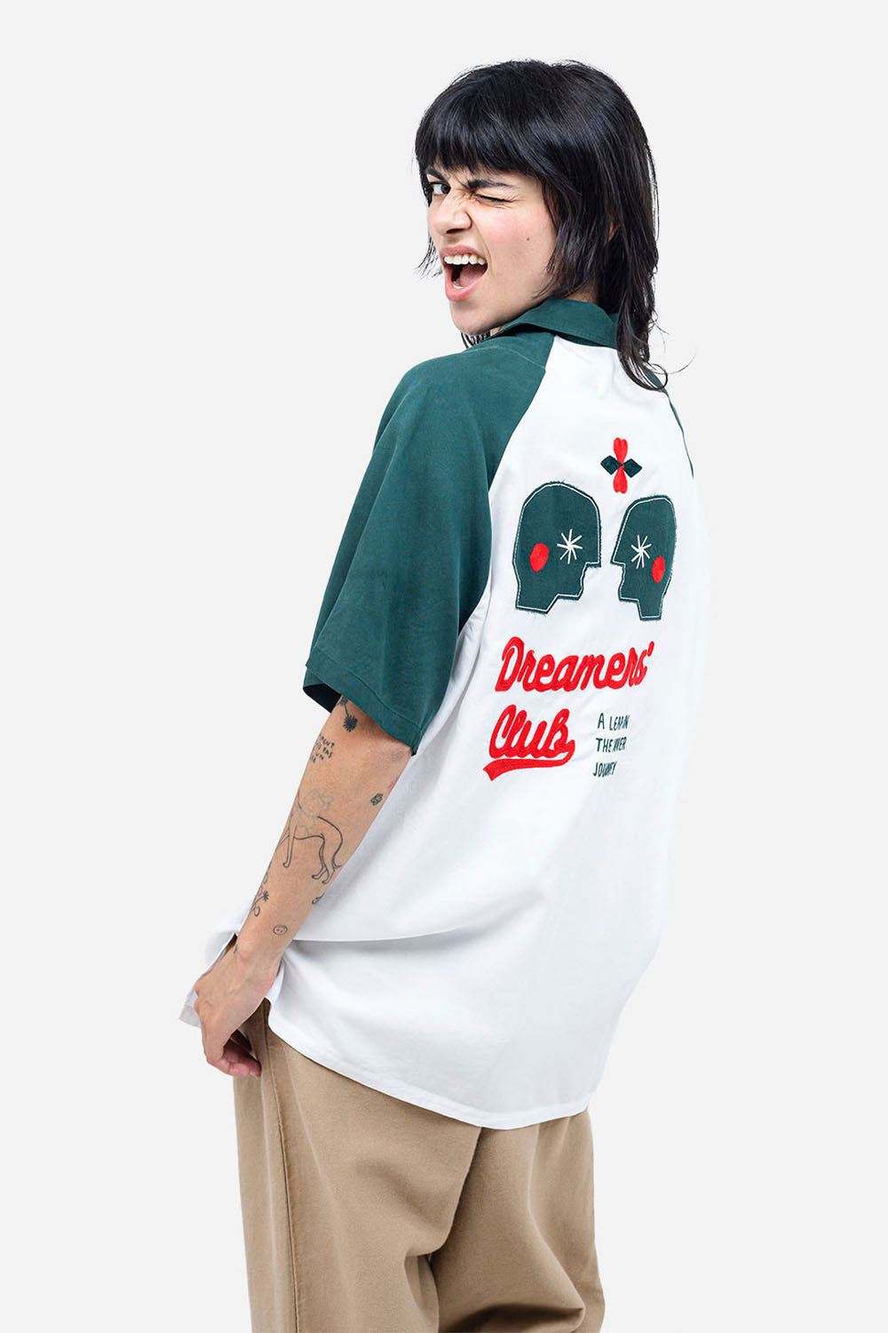 Person wearing a 'Dreamers Club' baseball shirt with graphic designs on a white background