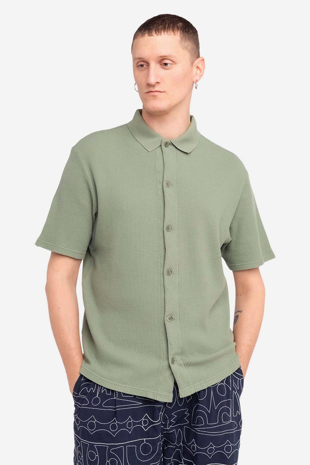 Person wearing a green short-sleeve shirt with a collar on a white background