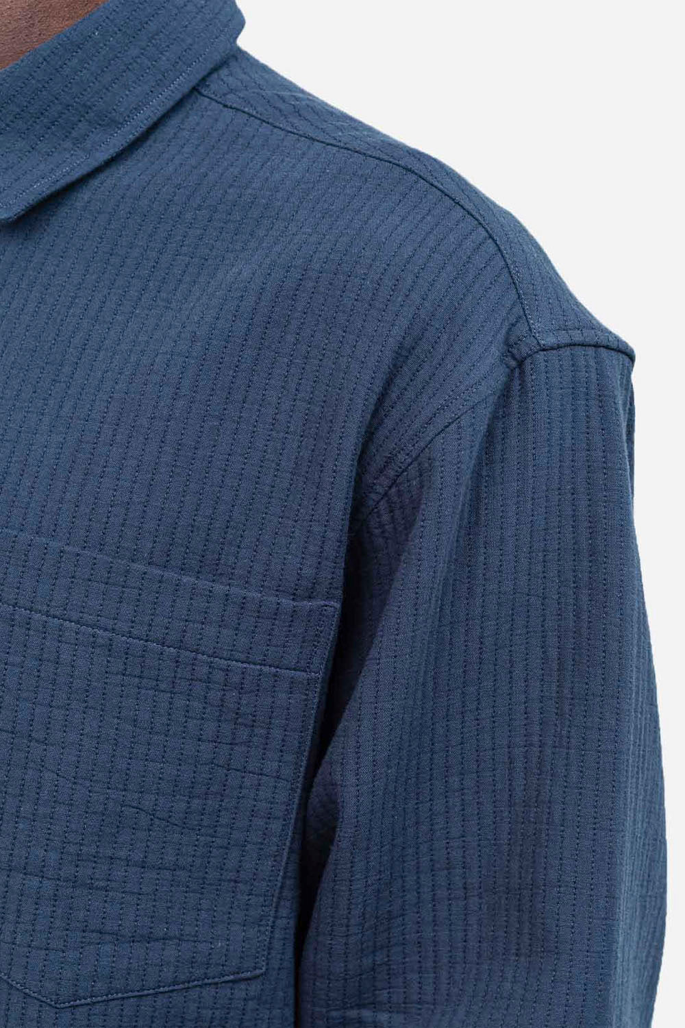 Close-up of a blue textured shirt with a pocket on a white background