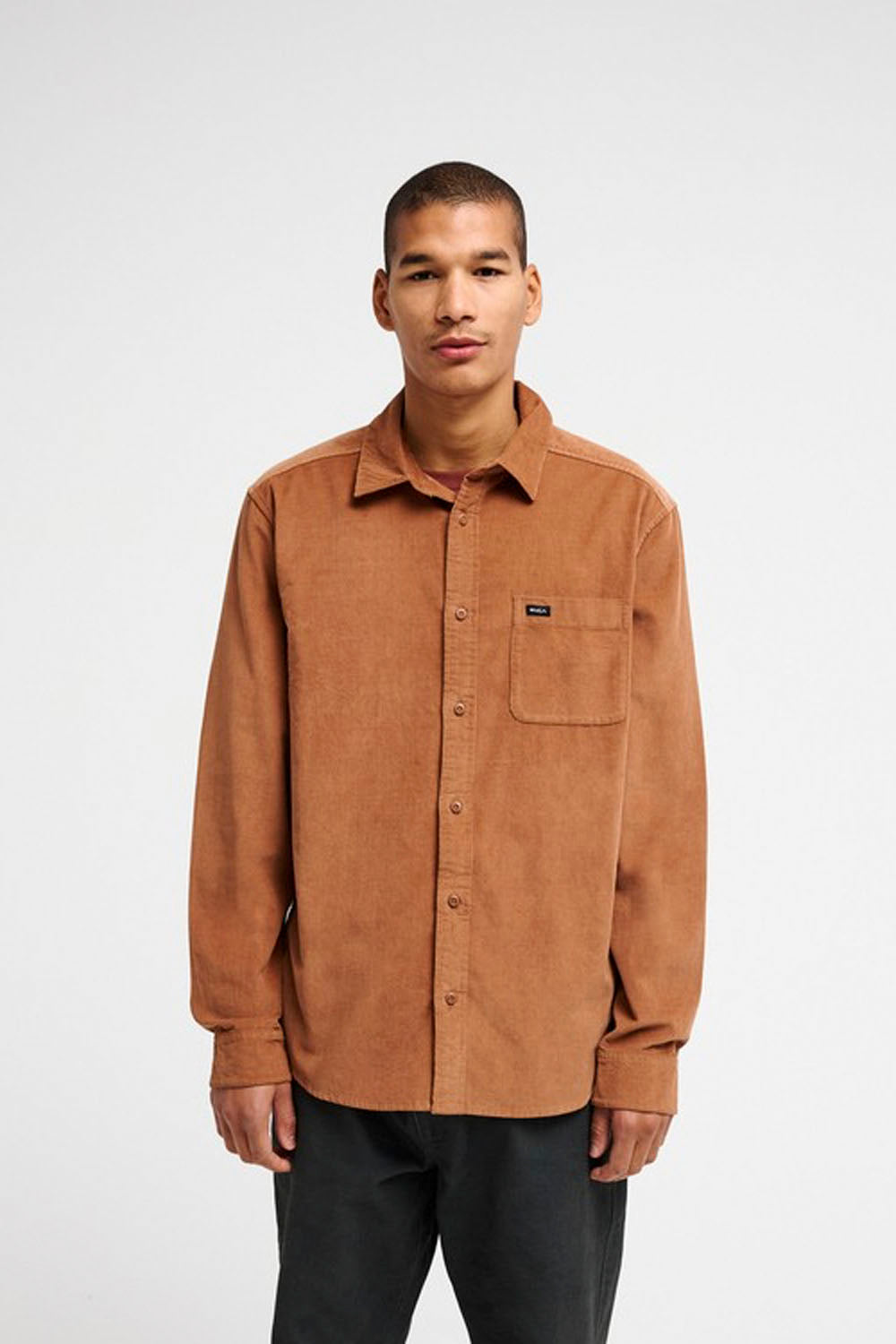 A man modeling a brown corduroy button-up shirt on a white background