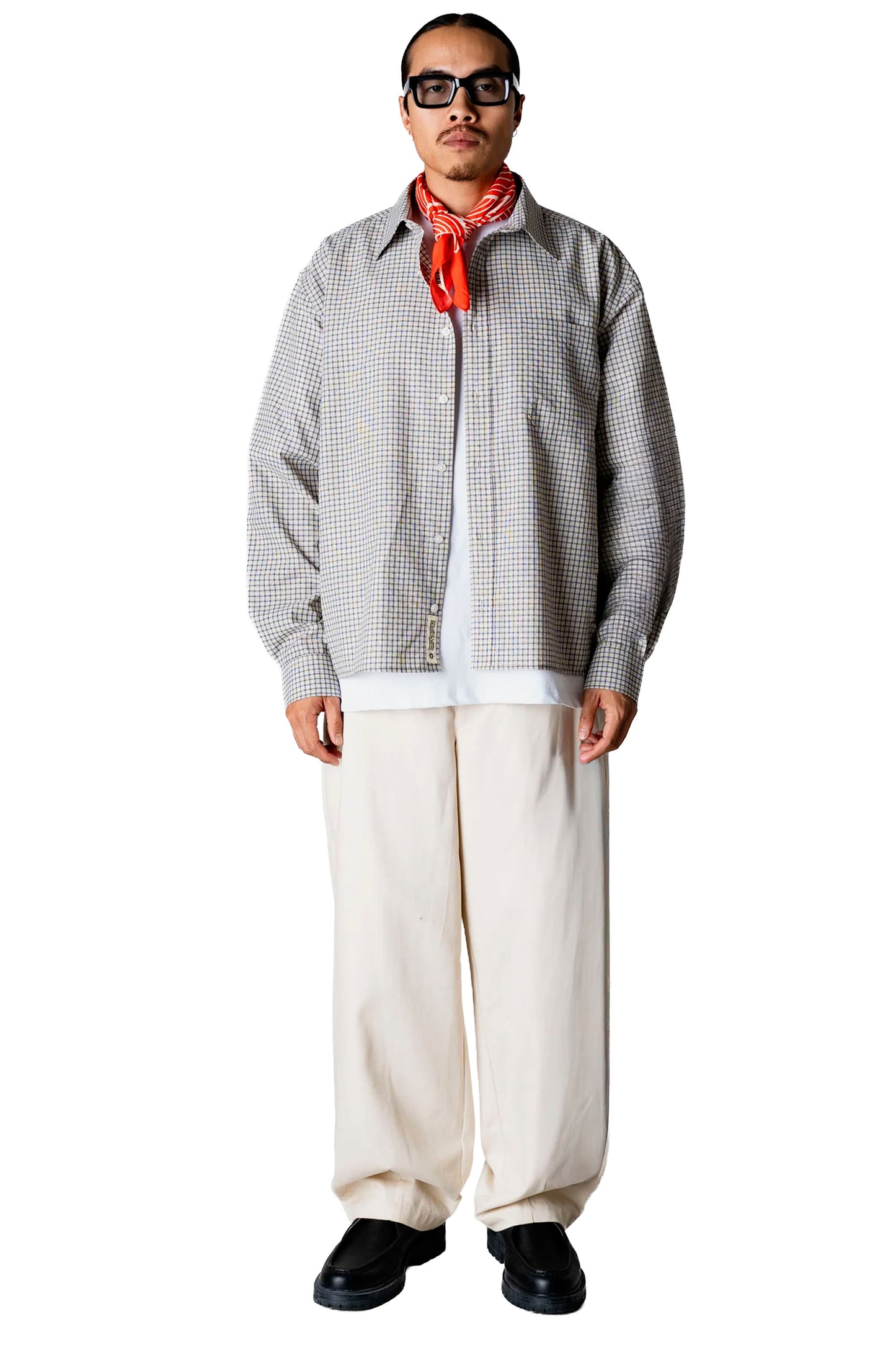 Person wearing a Woodbird Wbbuzo Check shirt, white pants, and black shoes on a white background