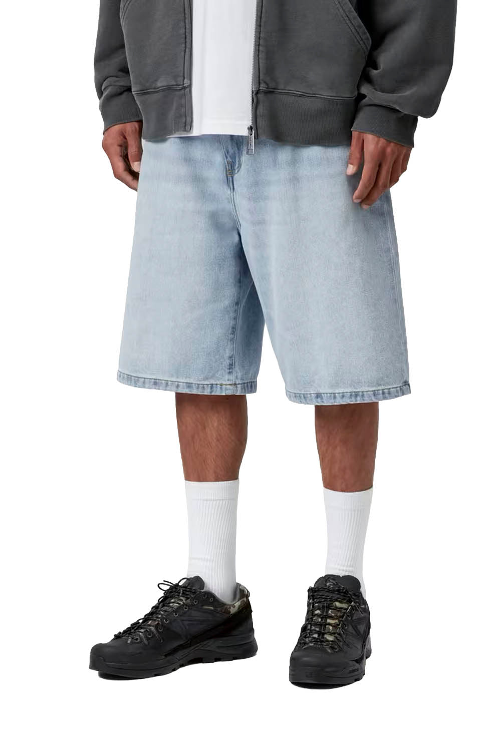 Person wearing light blue denim shorts, black sneakers, and white socks on a white background