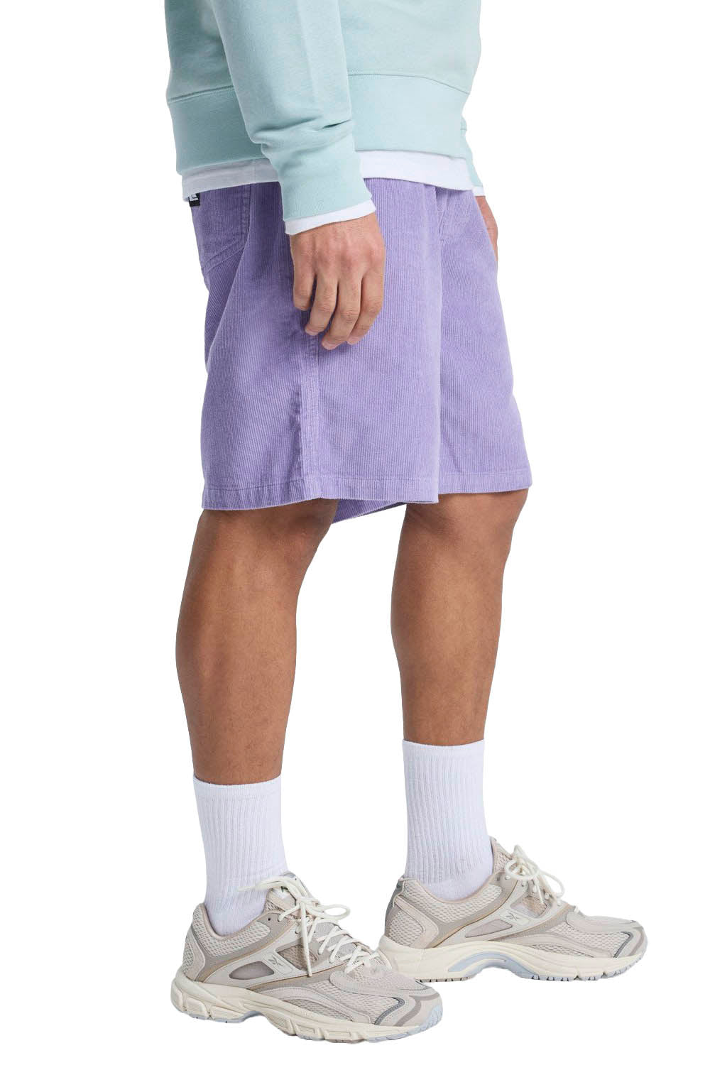 Person wearing a light purple skirt, light blue sweatshirt, white socks, and beige sneakers on a white background