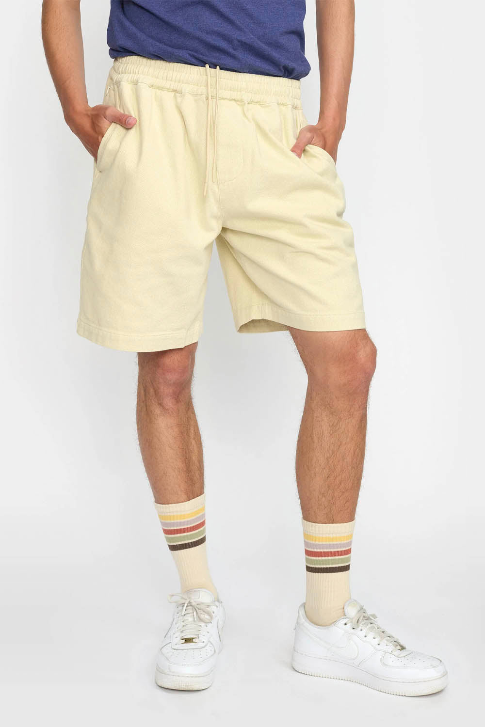 Person wearing light yellow shorts and colorful striped socks on a white background