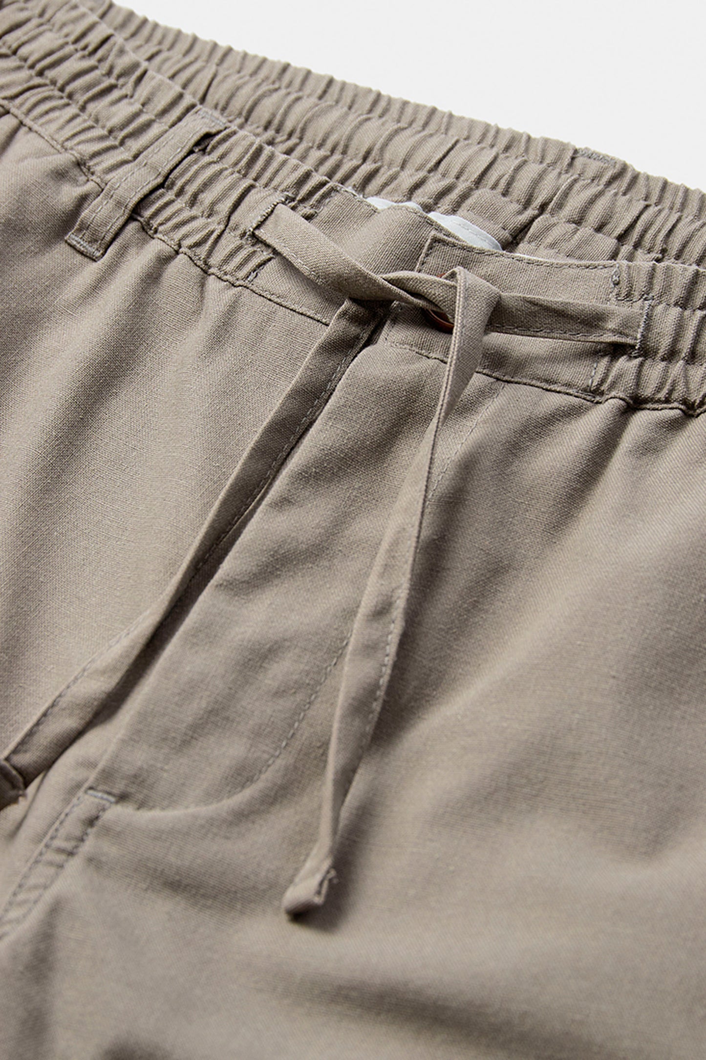 Close-up of beige shorts with an elastic waistband on a light gray background