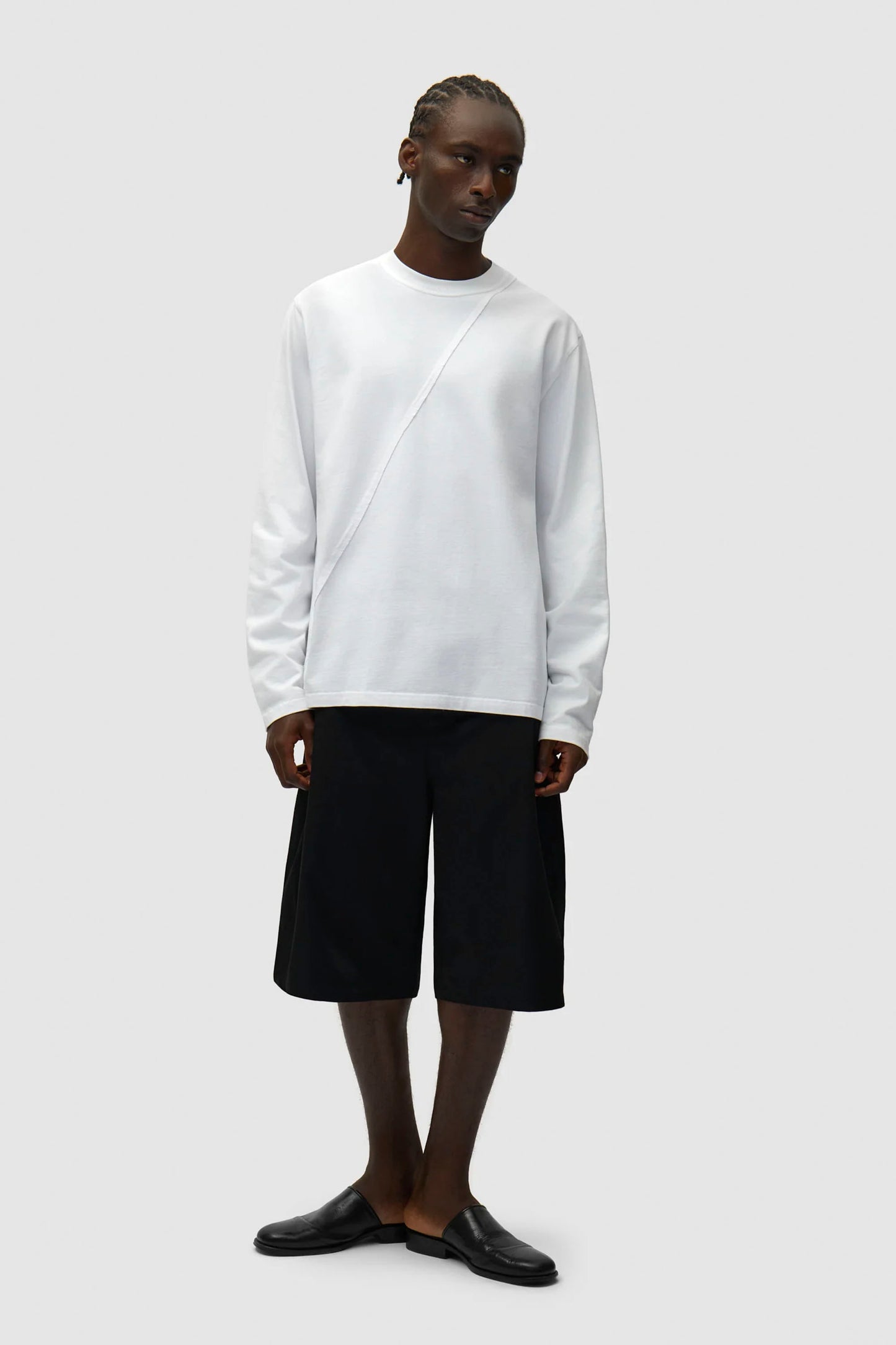 Person wearing a white sweater andARTE Classic Shorts in black on a white background