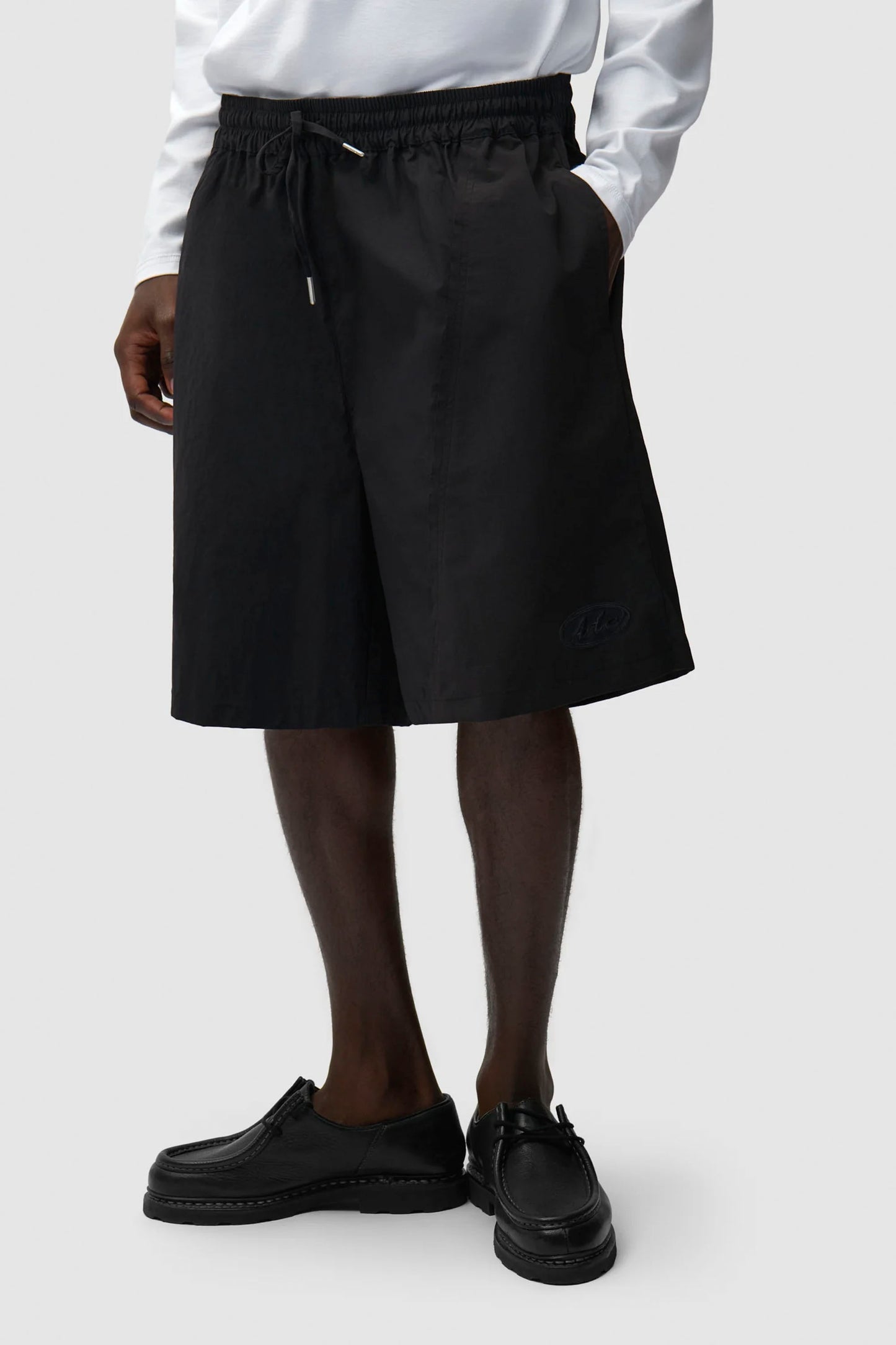 Person wearing a ARTE Distorted Shorts Black with a white shirt on a plain background